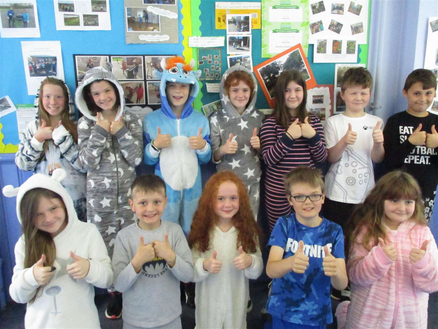 Some of the P5 children give a thumbs-up to wearing their pyjamas and onesies to school.