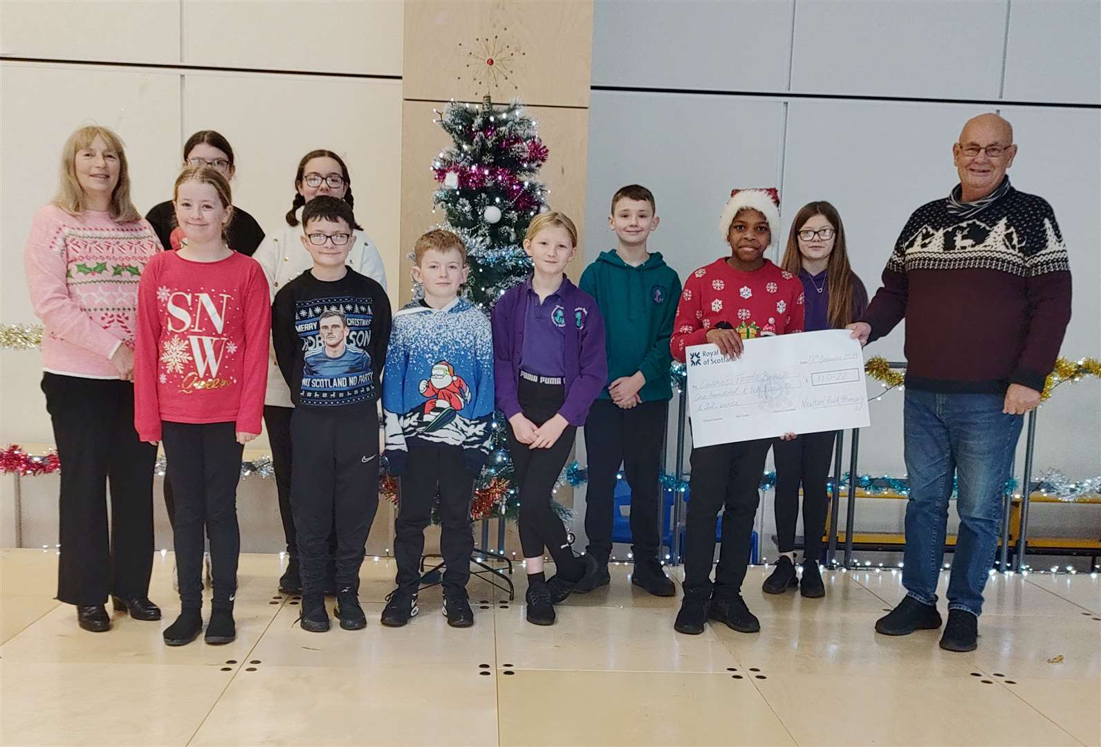 Caithness Foodbank's Grant Ramsay receiving a cheque for £110.22 from pupil council members at Newton Park Primary School.