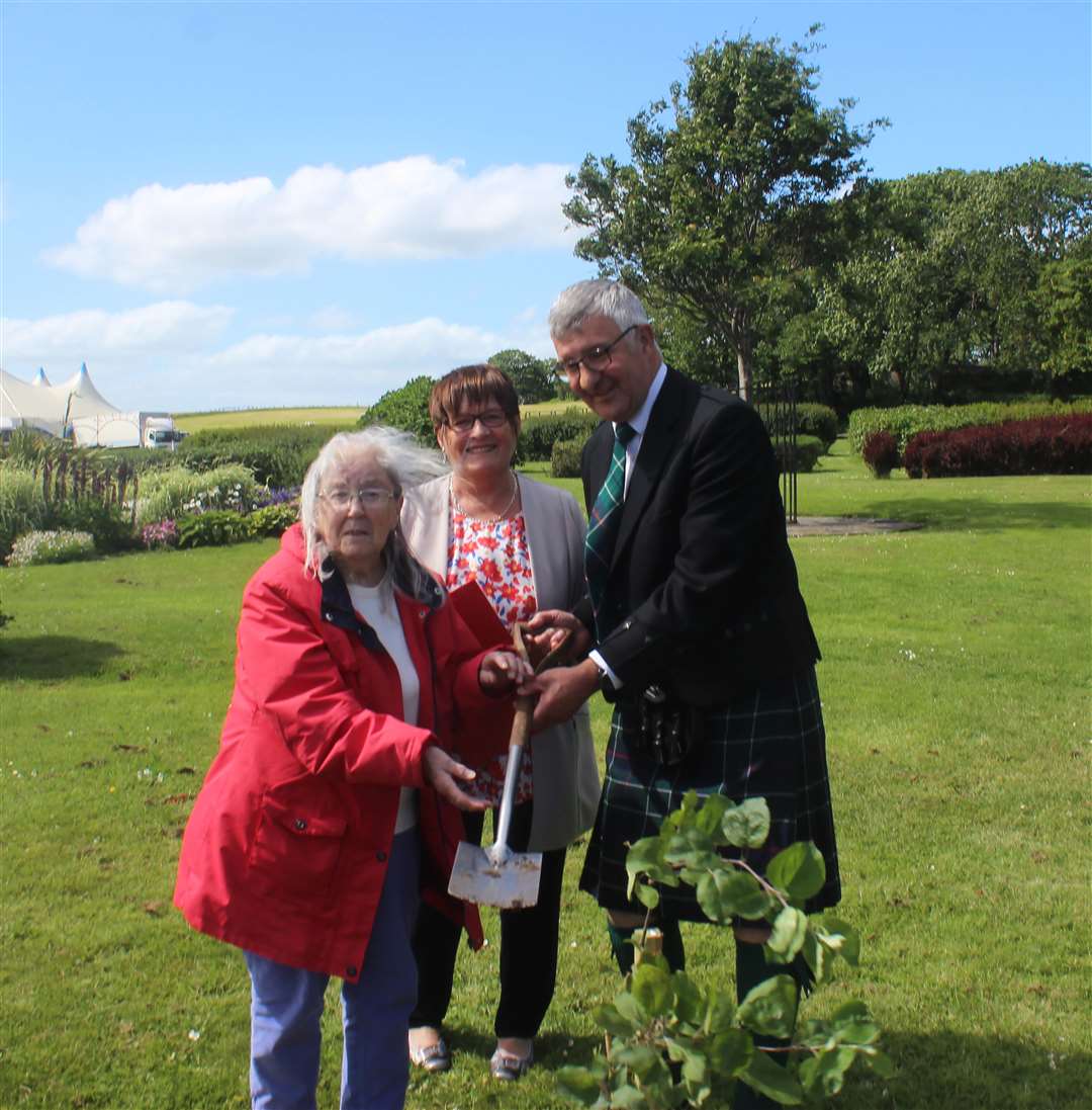 Olive Whittlesea (left) planting one of the trees, assisted by Willie Watt, with club chairperson Doreen Turner looking on.