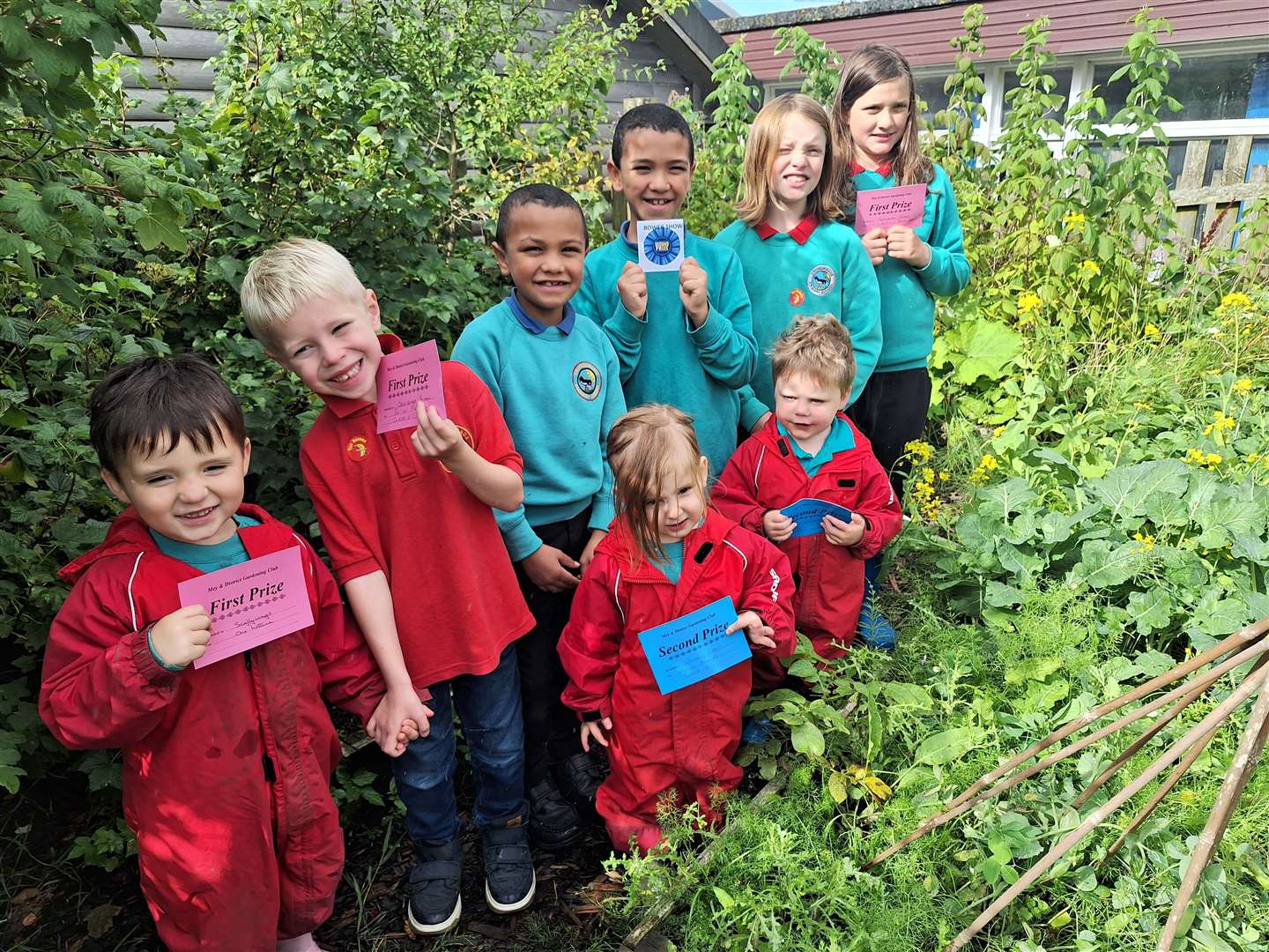 Pupils at Crossroads Primary and Scallywags ELC in their garden with their show prize certificates.