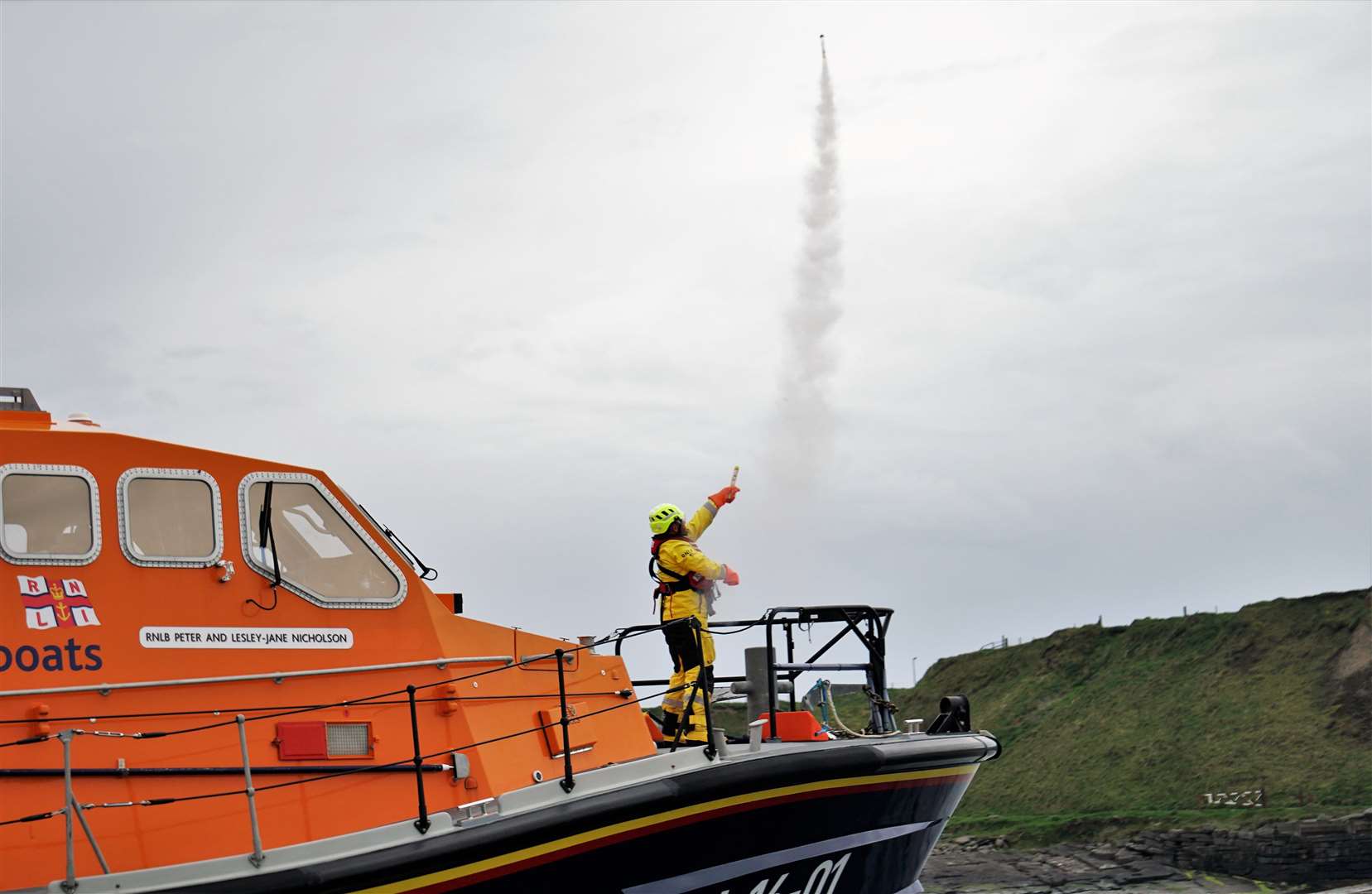 A Longhope lifeboat crew member letting off a flare in Wick Bay. Picture: DGS
