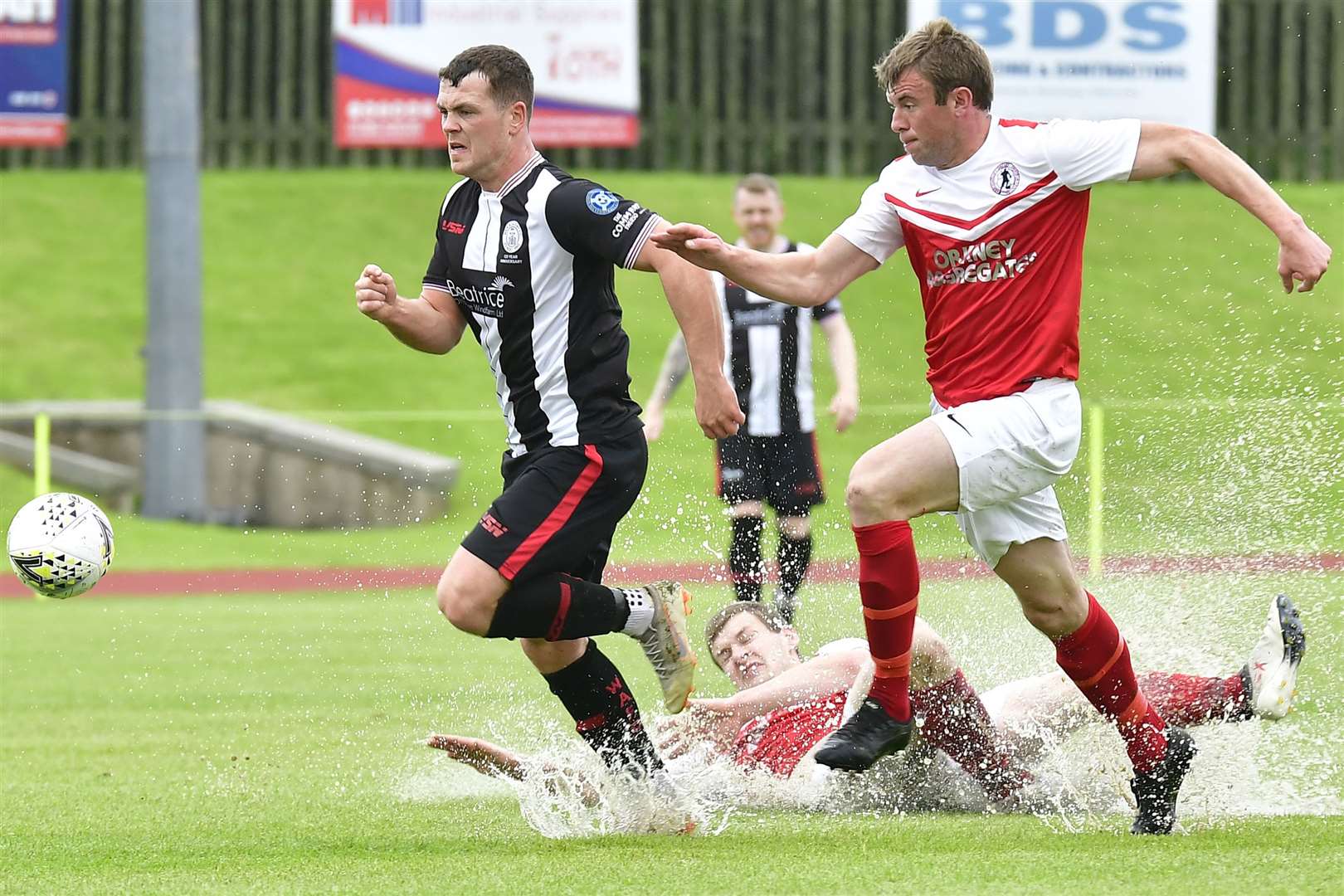 Orkney's Owen Rendall goes for a swim as Jon Tait and Wick's Gordon MacNab chase the ball. Picture: Mel Roger