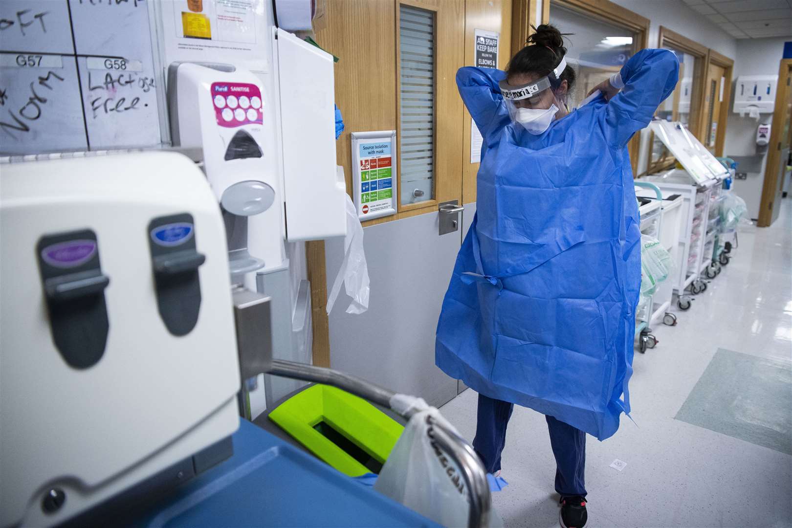 A staff nurse puts on PPE in the corridor (Victoria Jones/PA)