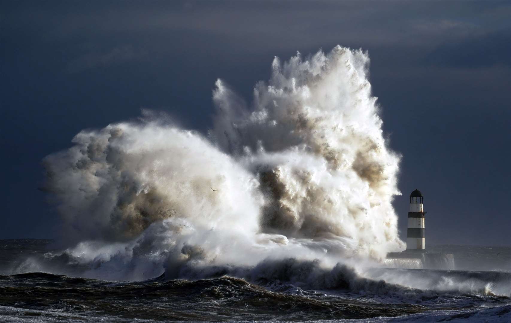 Waves crash against the lighthouse in Seaham Harbour, County Durham (PA)