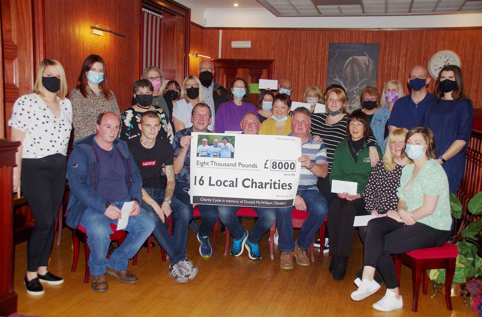 Representatives of the 16 good causes at the handover event in the Seaforth Highlanders' Club in Wick, with charity cyclists Willie MacDonald (seated, centre) and Arthur Bruce (seated, centre right), back-up drivers Neil Pellow (seated, centre left) and Martin Gibson (seated, second from left), along with Donald (Tender) McWilliam's daughters Lynne Davidson (front left) and Lauren McWilliam (seated, far right). Picture: Ian McDonald
