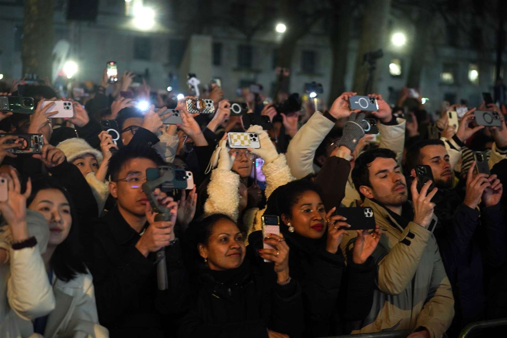 The crowd get their pictures of the fireworks over the London Eye in central London during the new year celebrations (Victoria Jones/PA)