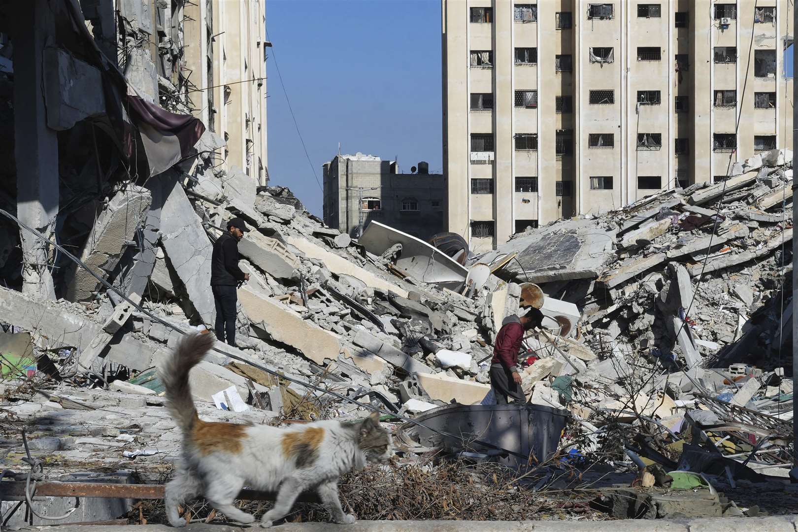 Palestinians walk through destruction from the Israeli bombardment in the Nusseirat refugee camp in the Gaza Strip on Friday (Adel Hana/AP)