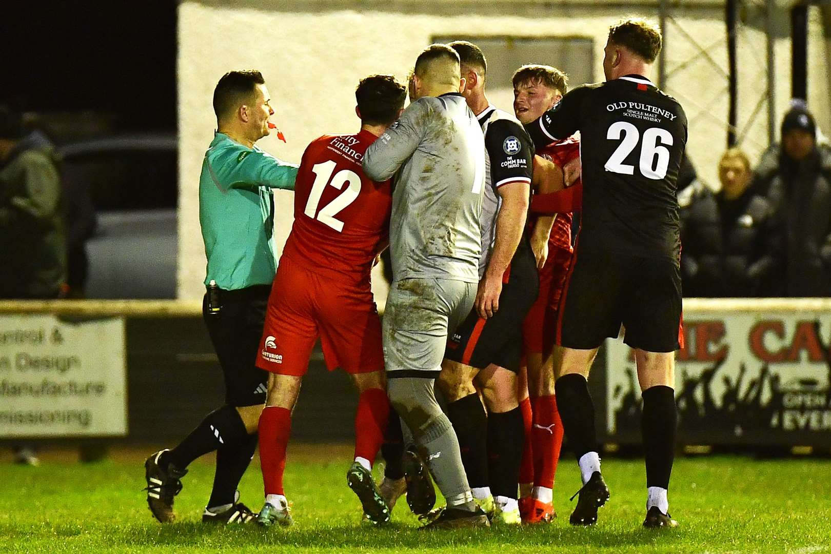 Referee Billy Baxter steps into separate Wick and Brora players during Wednesday night's far north derby. Picture: Mel Roger