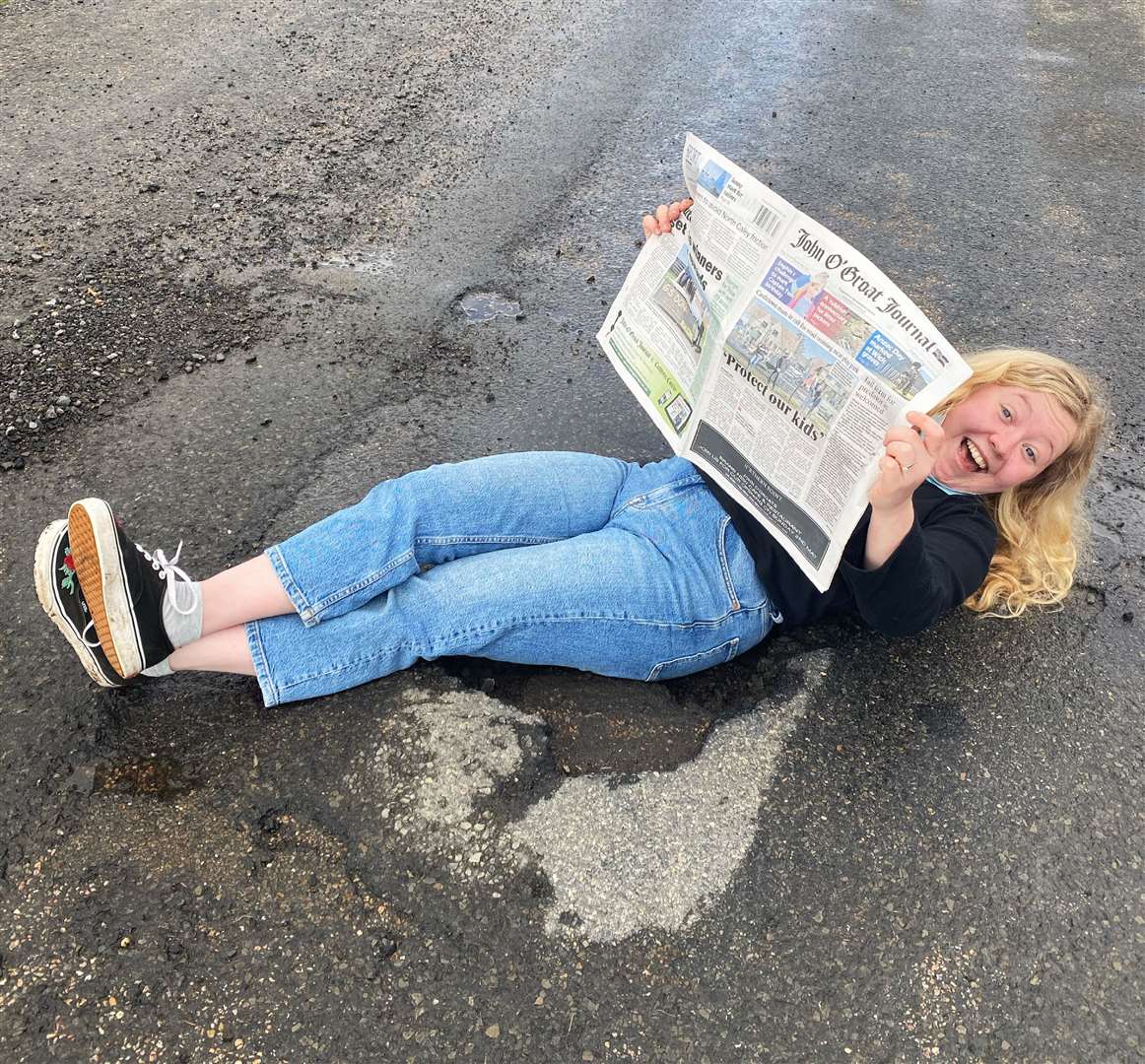 Enya Evans reading the Groat in a Lybster pothole. She could see the funny side, but was also keen to make a serious point about the state of the county's roads.