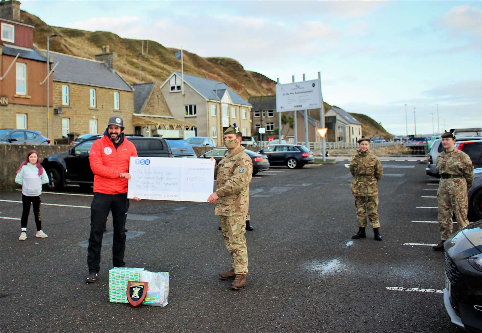 Sergeant Major Instructor Stuart Taggart (right) presenting Jordan with a £500 donation and a Caithness care package, alongside cadets who attended to lend support.