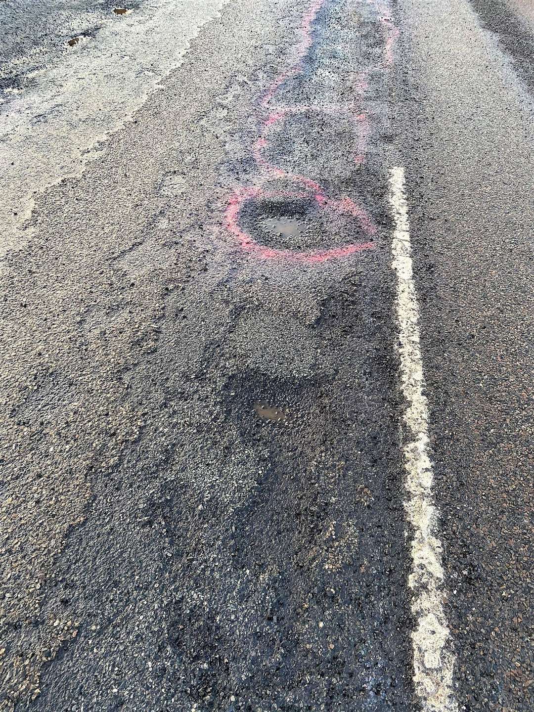Terri sprayed some florescent pink paint around the worst potholes to warn other drivers. Pictures: Terri Munro