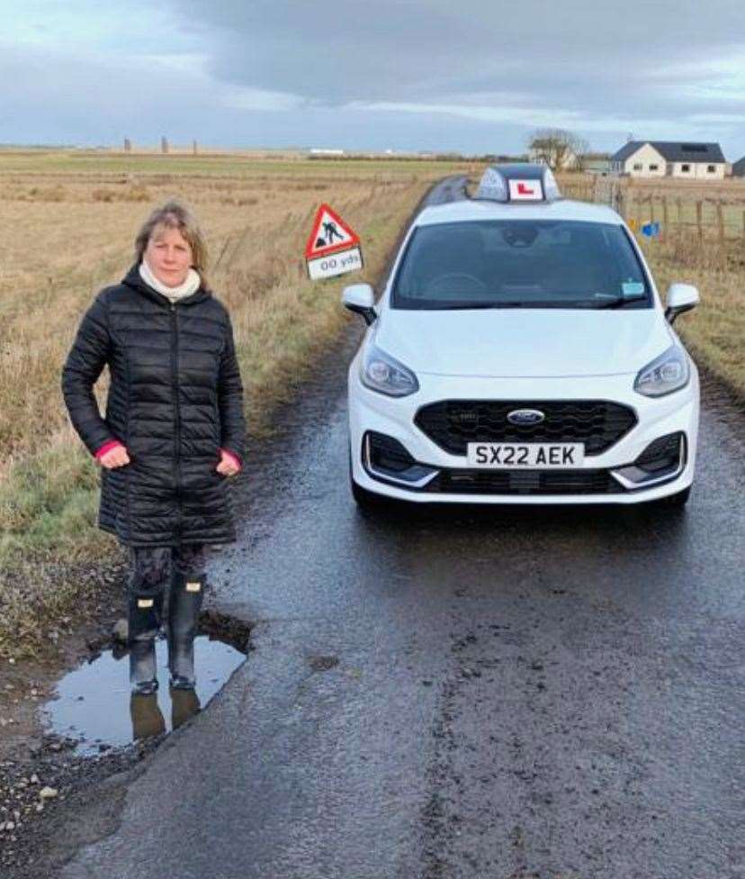 Debbie Aitkenhead in her wellies, standing in a pothole at the side of the road at Newton.