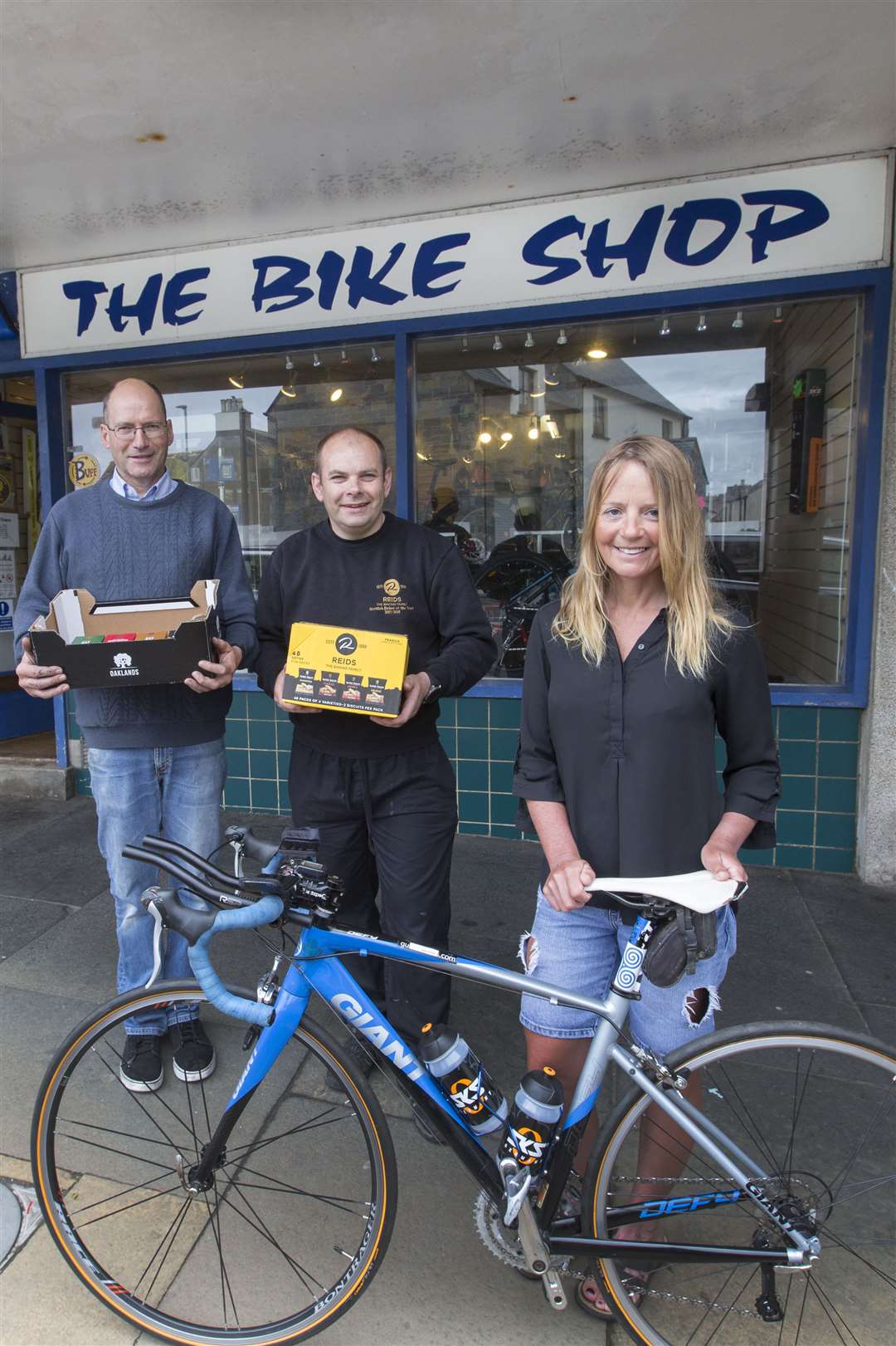 Lorna Stanger collects one of the two bikes that are being prepared for her duathlon. Looking on are Sam Robinson (left), from The Bike Shop, and Gary Reid of Reid's Bakery, which is providing some snacks for the journey. Picture: Robert MacDonald / Northern Studios