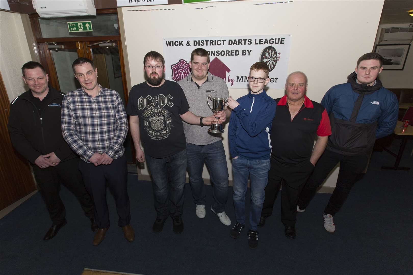 The Ray Sinclair Memorial Cup men's competition was won by Wick and District Darts League second division players Chris Scott and Eean Ronaldson (Sinclair Bay), who defeated the first division pair of Ronnie Plowman and Damon Meikle (Seaforth). Ray's grandson, Craig, is pictured handing the trophy to Eean (centre) and Chris (centre left), while looking on are losing finalists Ronnie (second right) and Damon (right), along with Ray's sons Gary (left) and Graeme. The competition was held in Harper's Bar on Tuesday night. Picture: Robert MacDonald / Northern Studios