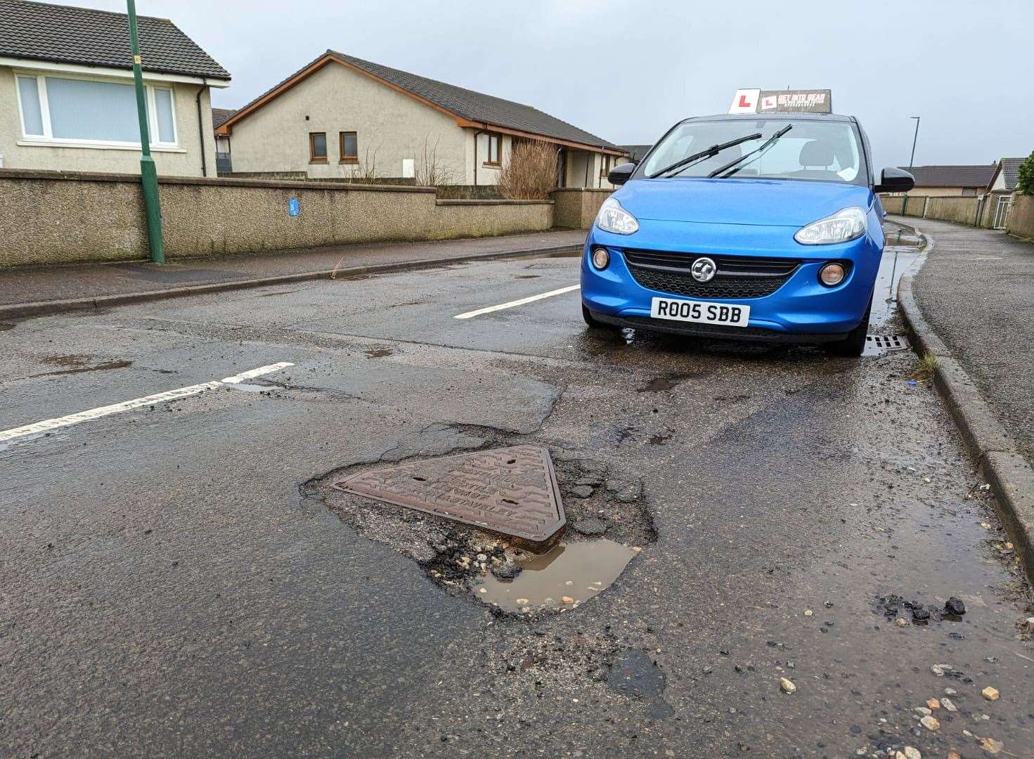 Ross Bain's tuition car beside a pothole in the Lindsay Drive area.
