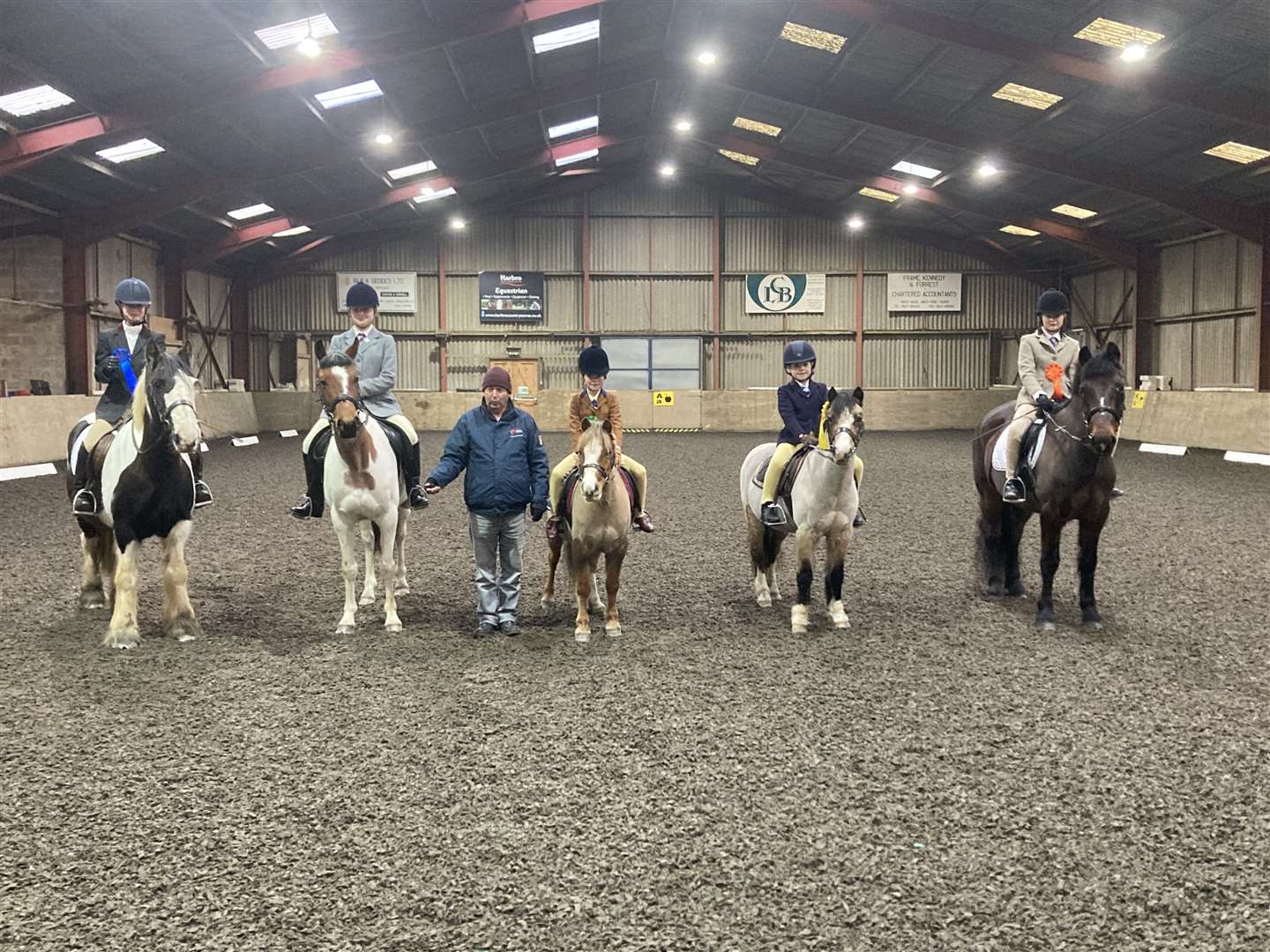 The competitors in the assisted D Level Dressage Test 2012 proudly show off their rosettes. From left to right: Jaicee Johnson, Jojo, Gina Cowe, Poppy, judge Stephen Cruickshank, Darcey Alexander, Titch, Rachel MacGregor, Dandy, and Sophie Thomson, Whisky.