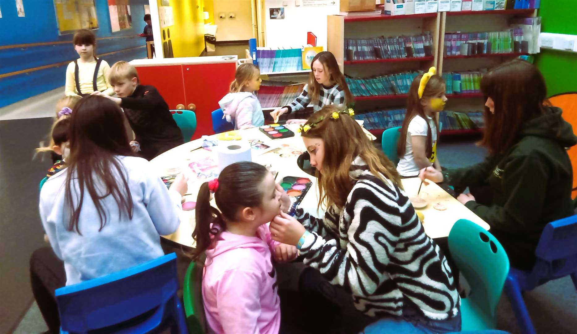 Primary 7 pupils paint the faces of younger pupils.