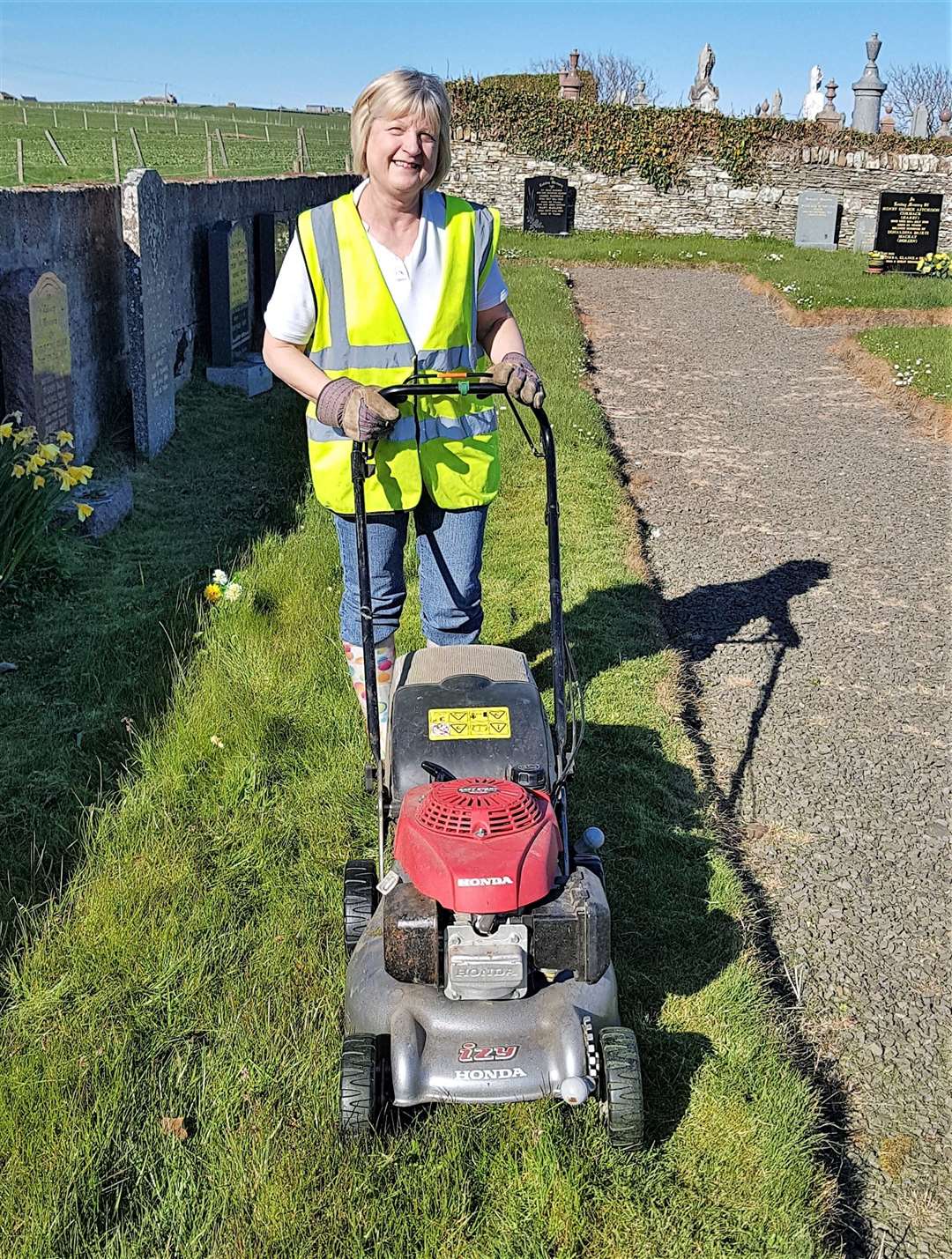 Glynis Mackay cutting the grass at Keiss cemetery.
