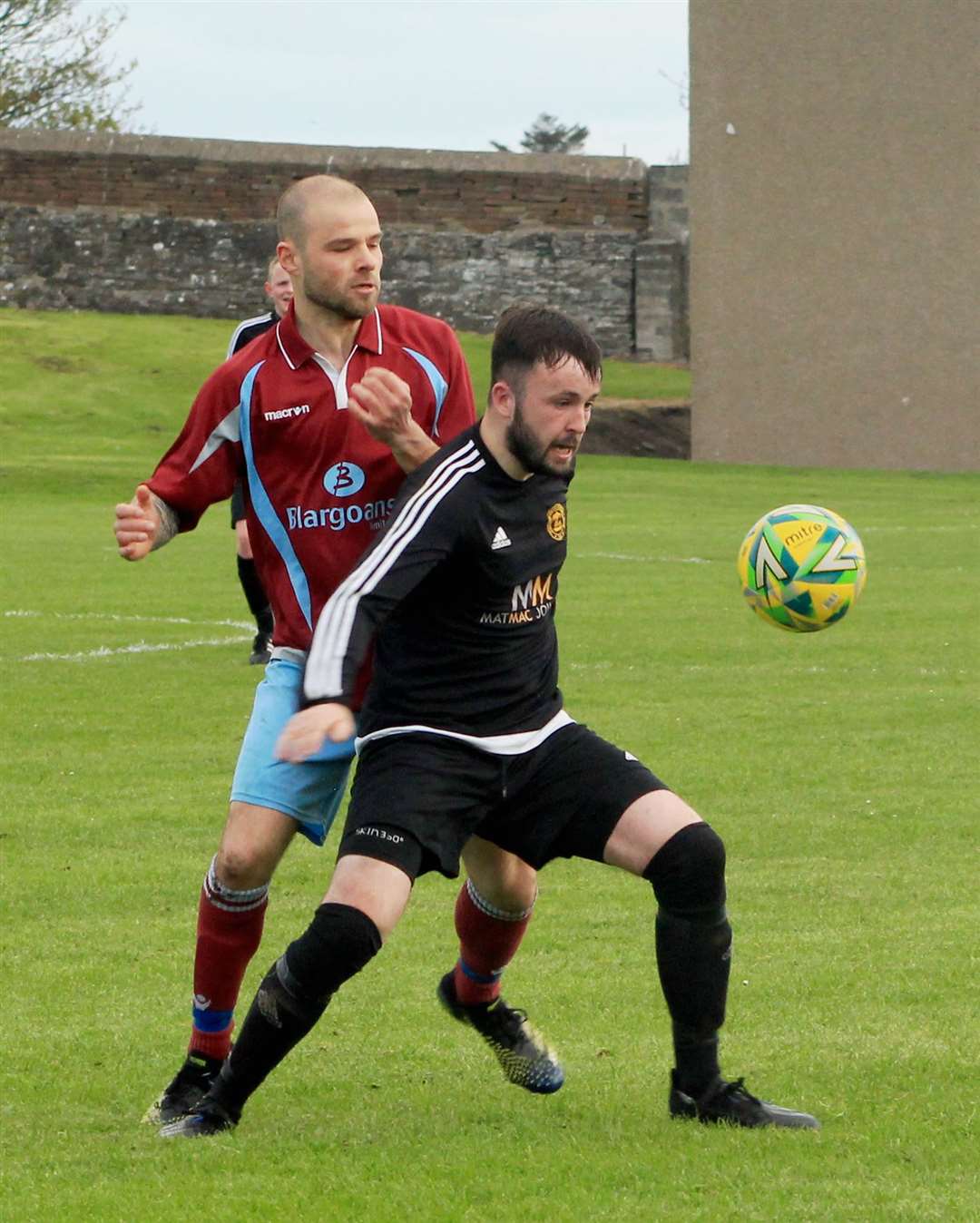 Staxigoe's Ross Davidson holding off a challenge from Sean Munro of Pentland United.