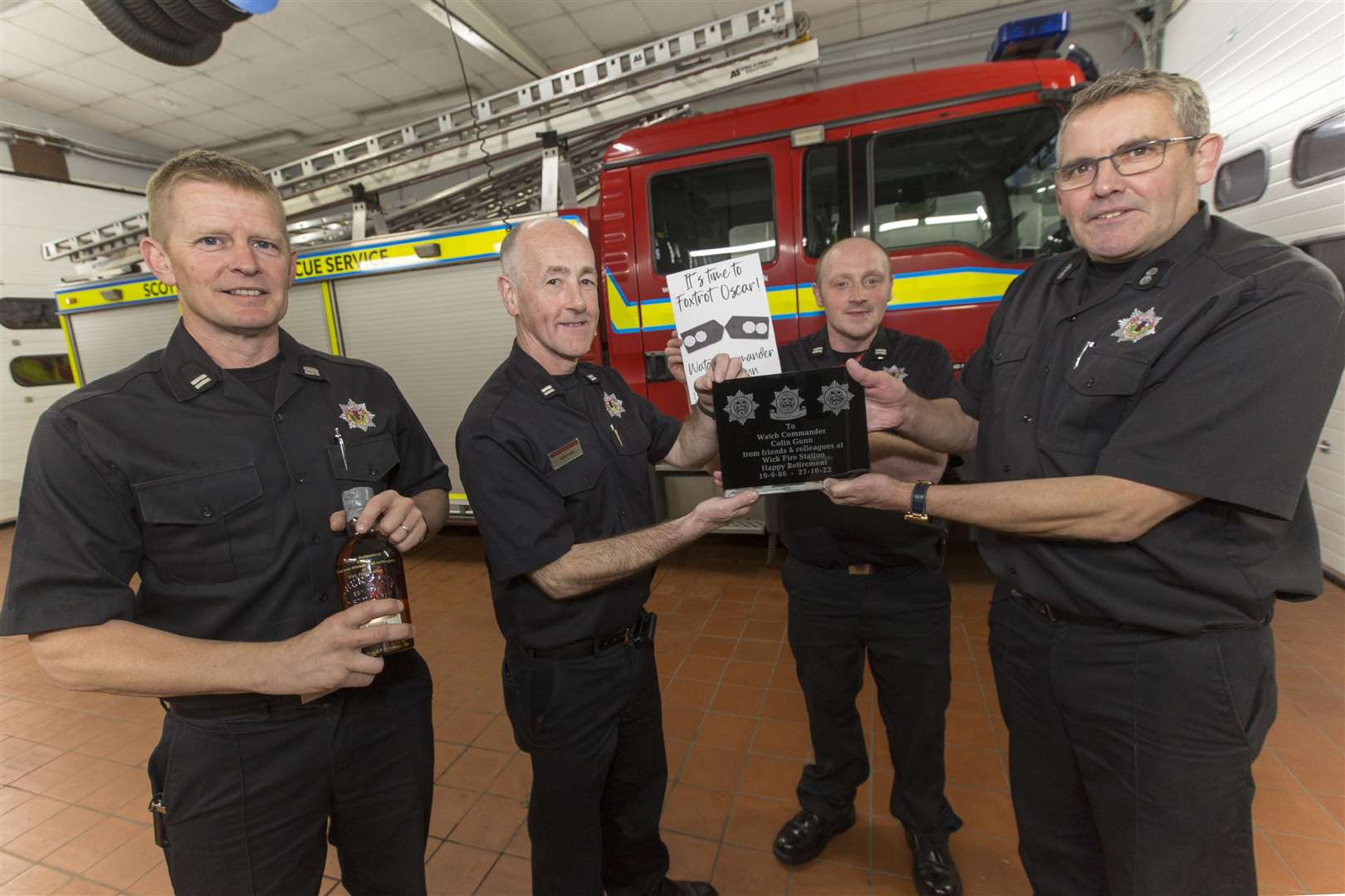 Colin (right) receives an engraved glass plaque from acting Watch Commander Hugo Ross, while Crew Commander Graeme Miller (left) hands over an engraved bottle of whisky and Crew Commander John Dunnett presents a retirement card signed by the crew members. Picture: Robert MacDonald/Northern Studios