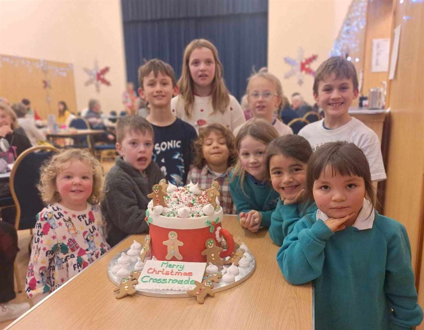 Pupils of Scallywags ELC and Crossroads Primary present the cake to the community.