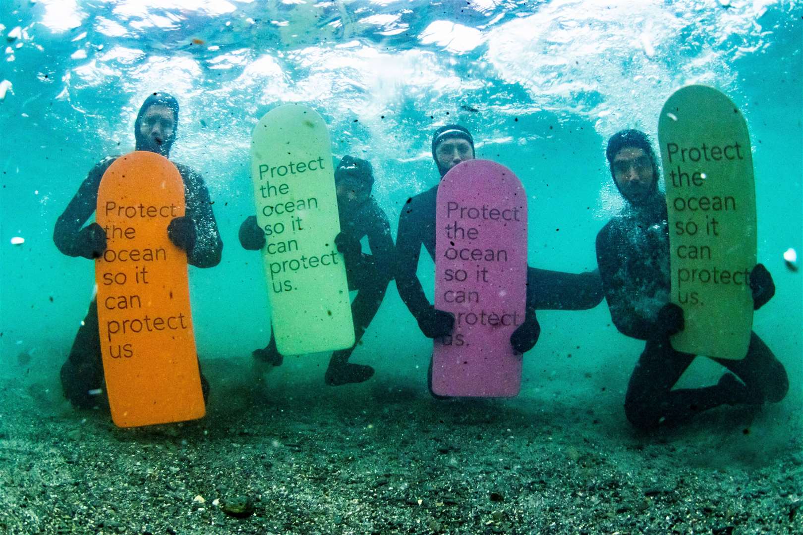 Phoebe Strachan (second from right, holding the pink sign) under the waves in Caithness with (from left) Frank Solomon, Patch Wilson and Arthur Bourbon. Picture: Al Mackinnon