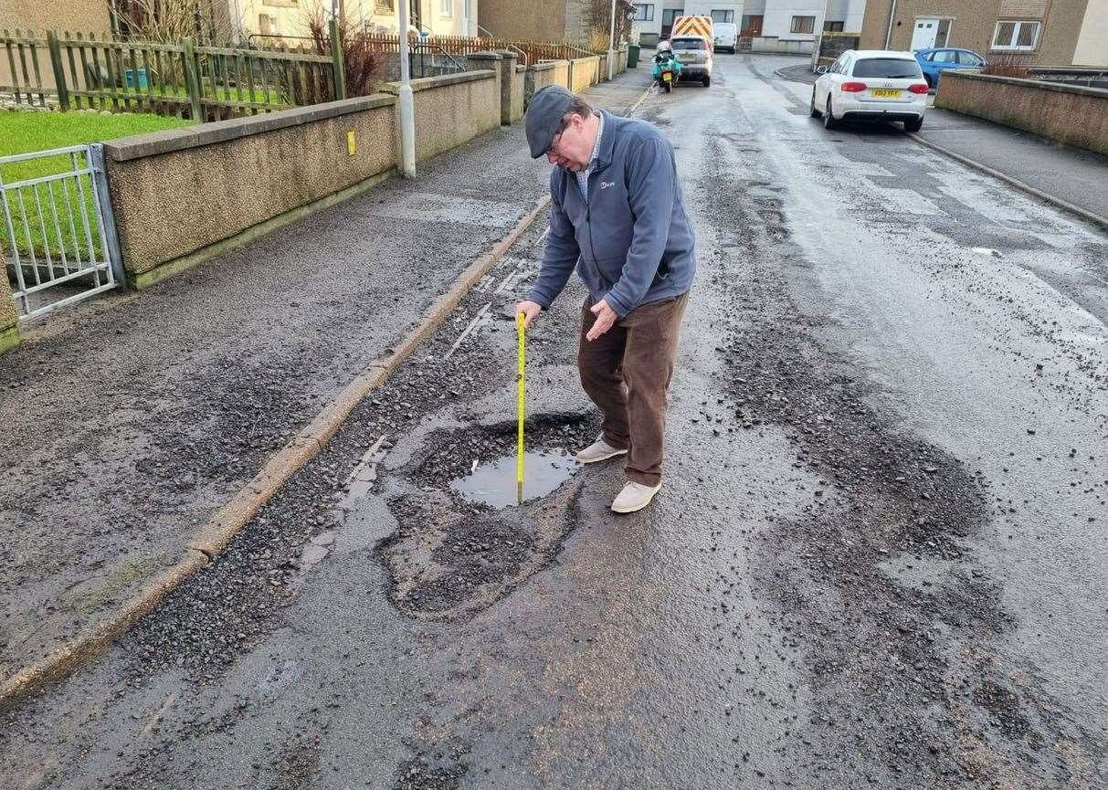 Driving instructor Bruce Paterson measuring a six-inch-deep pothole in Glamis Road, Wick.
