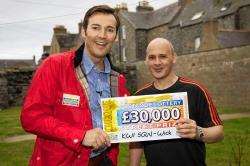 People’s Postcode Lottery presenter Angus Purden hands local man Andrew Malcolm a cheque for £30,000.