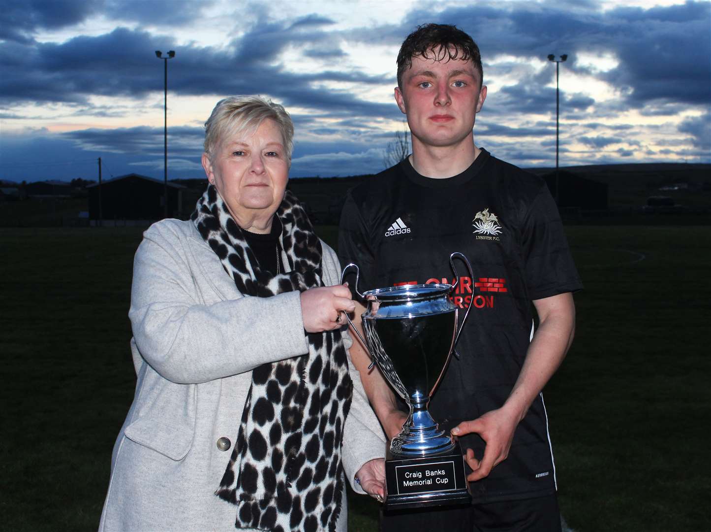 Susan Banks presenting the Craig Banks Memorial Cup to man of the match Alfie Mackay of Lybster. Picture: Alan Hendry