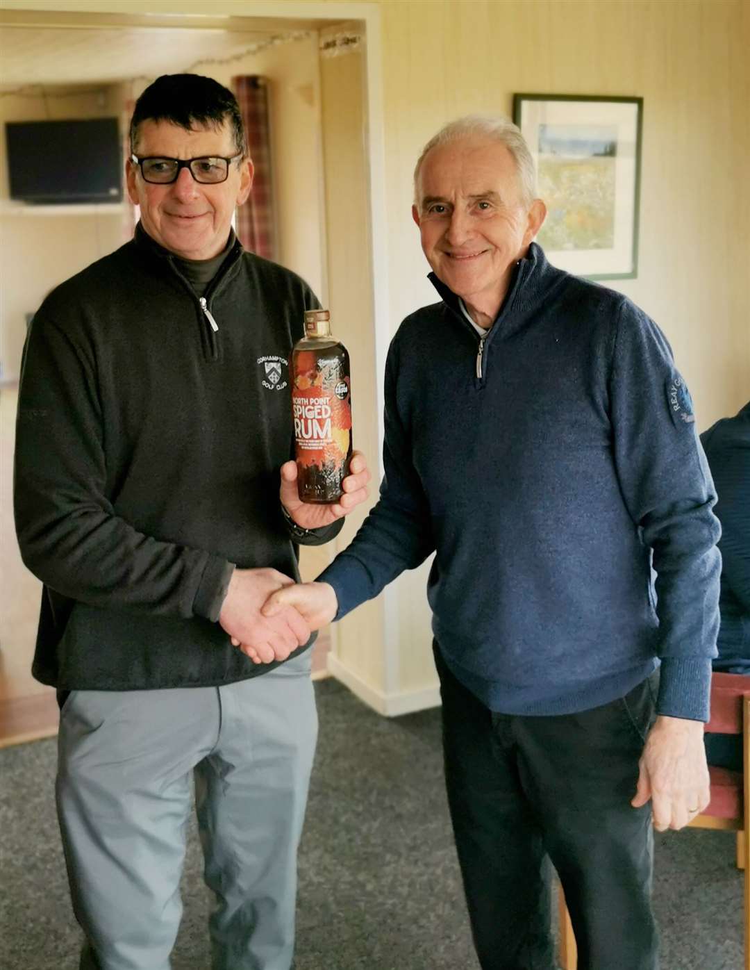 Malcolm Thomson (left) receiving a bottle of North Point Distillery Spiced Rum from Fred Groves after he won the nearest-the-pin prize in last Thursday's Senior Stableford competition at Reay.