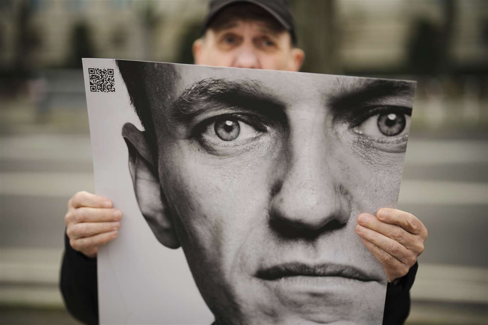 A man holds a poster with a portrait of opposition leader Alexei Navalny during a protest in front of the Russian embassy in Berlin (Markus Schreiber/AP)