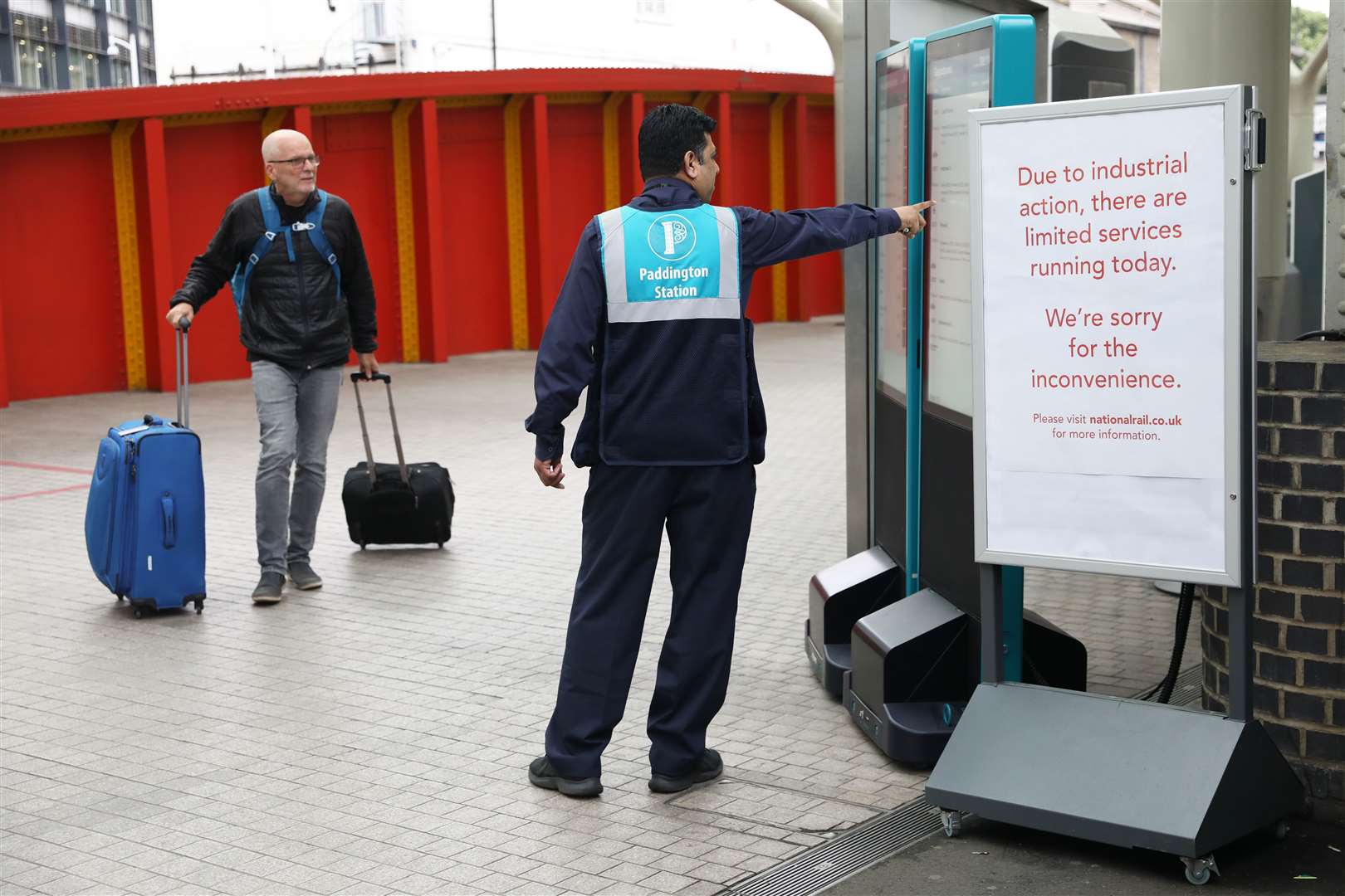 A station worker assists a passenger at Paddington station (Ashlee Ruggels/PA)