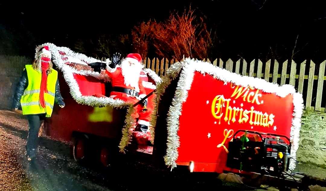 Santa waves to onlookers as he travels through the town in his sleigh.