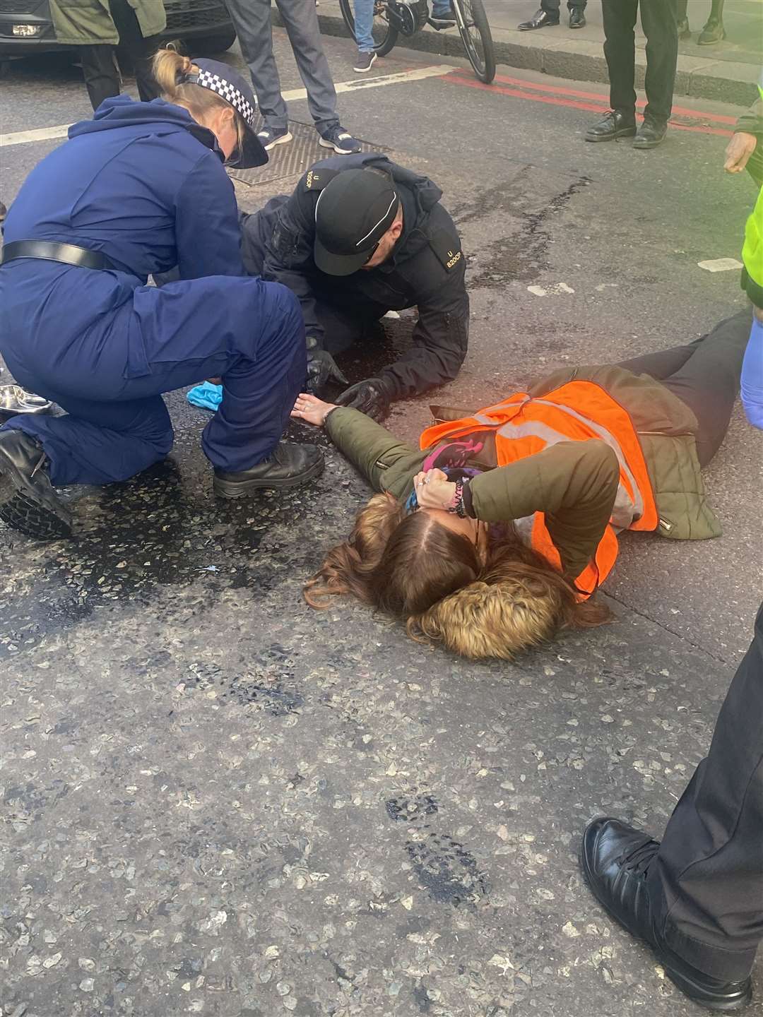 Metropolitan Police officers work to release a woman who has glued herself to the carriageway in Bishopsgate (Sophie Corcoran/PA)
