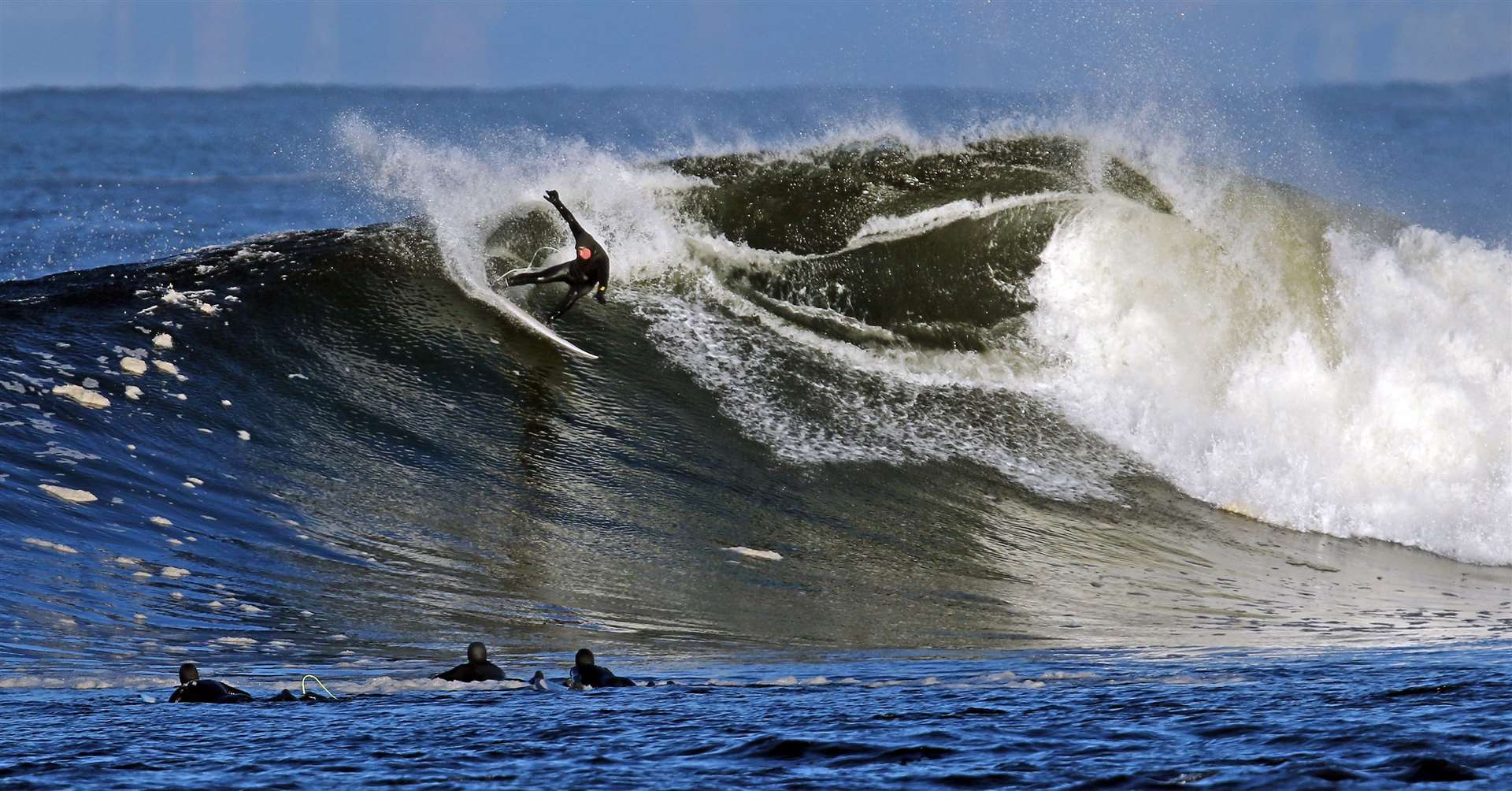 Thurso's Chris Noble is watched by fellow surfers while performing a snap turn at the top of a huge wave. Picture: James Gunn