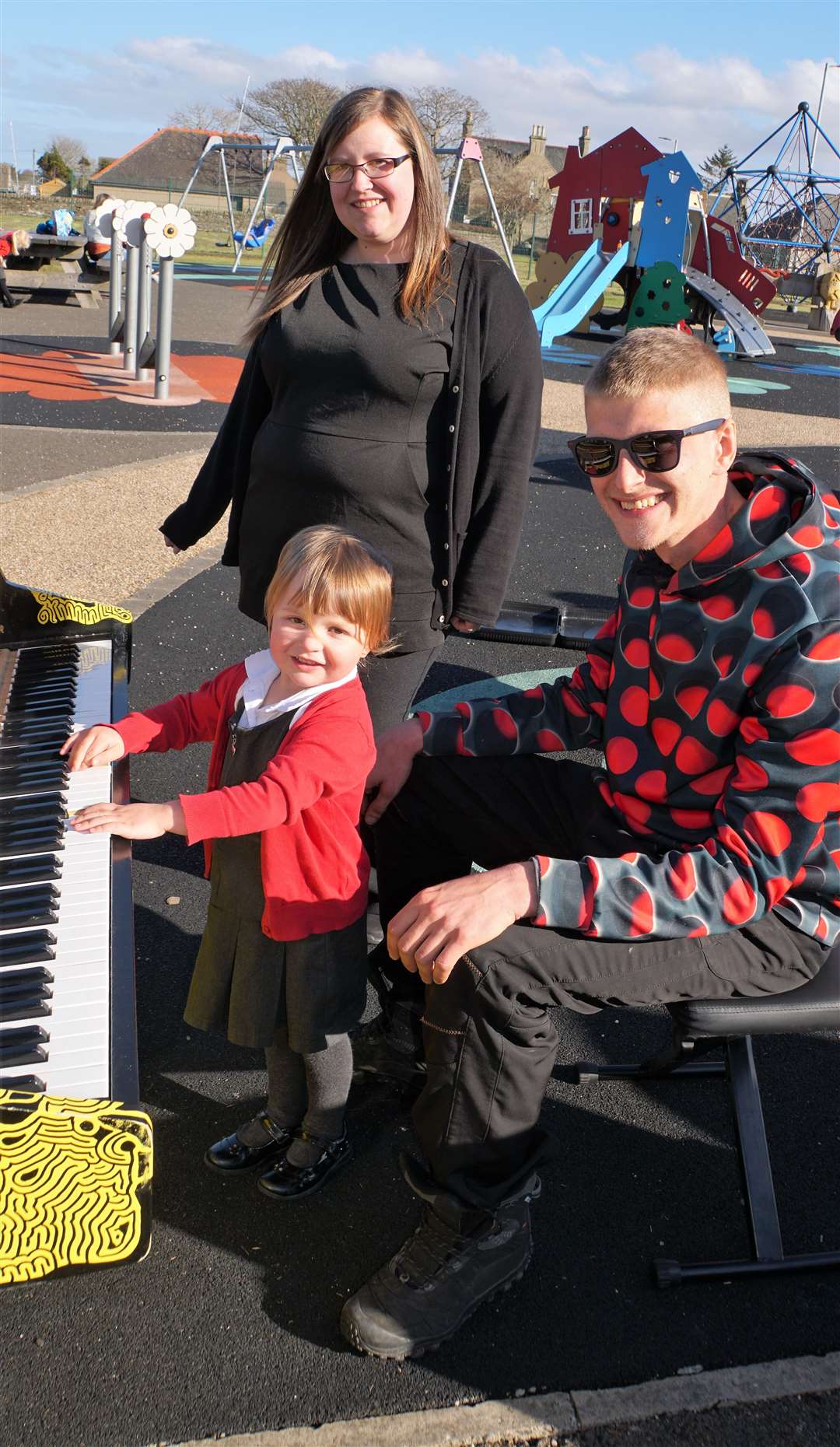 Emma Sewell with her daughter Lacey listen to James Tofalli play in the park.