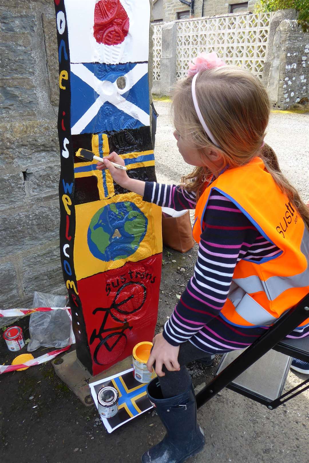 Ava painting the Caithness flag onto the route marker.