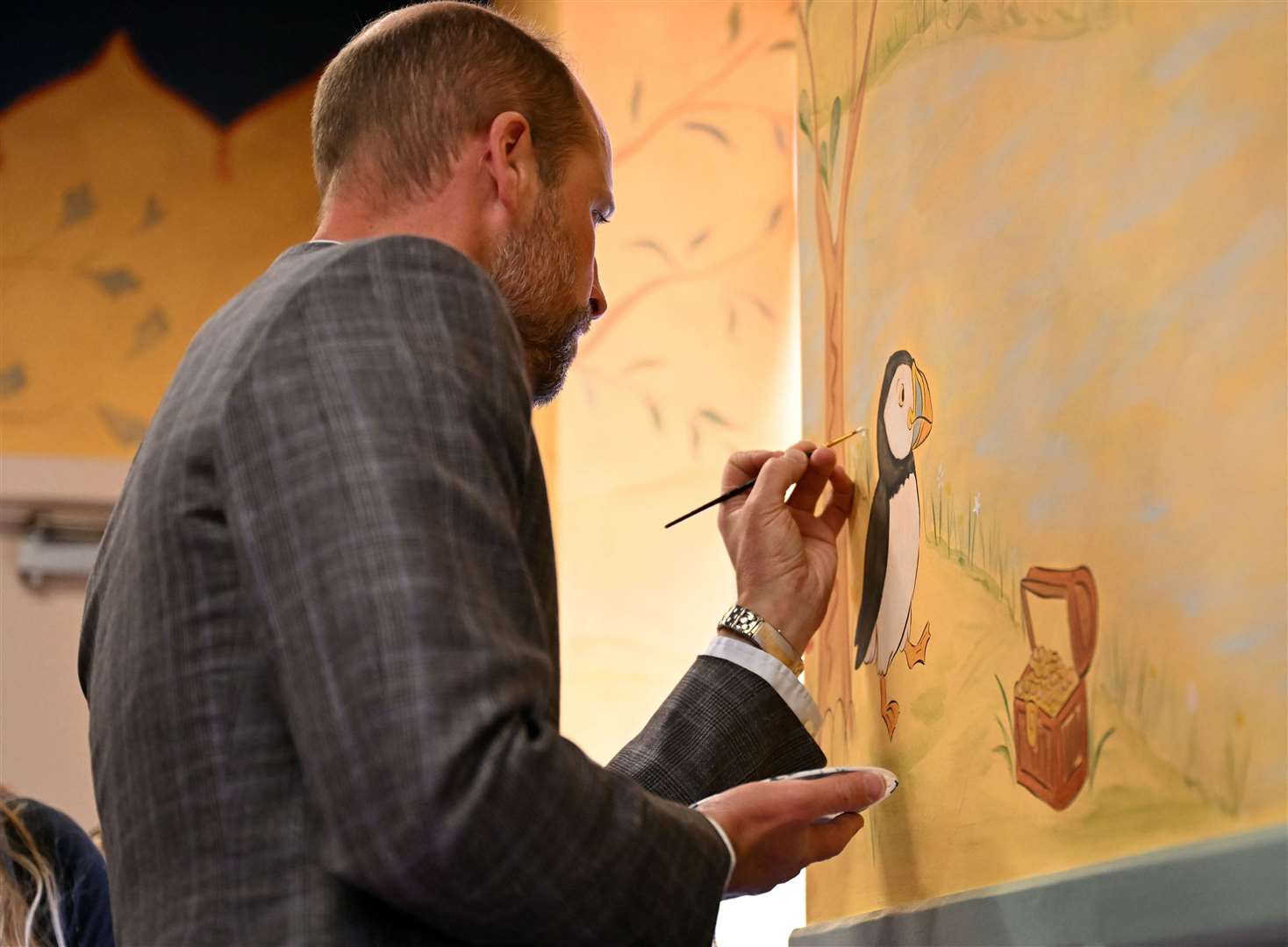 The Prince of Wales helped paint a children’s wall mural in the Aros hall community hub (Oli Scarff/PA)
