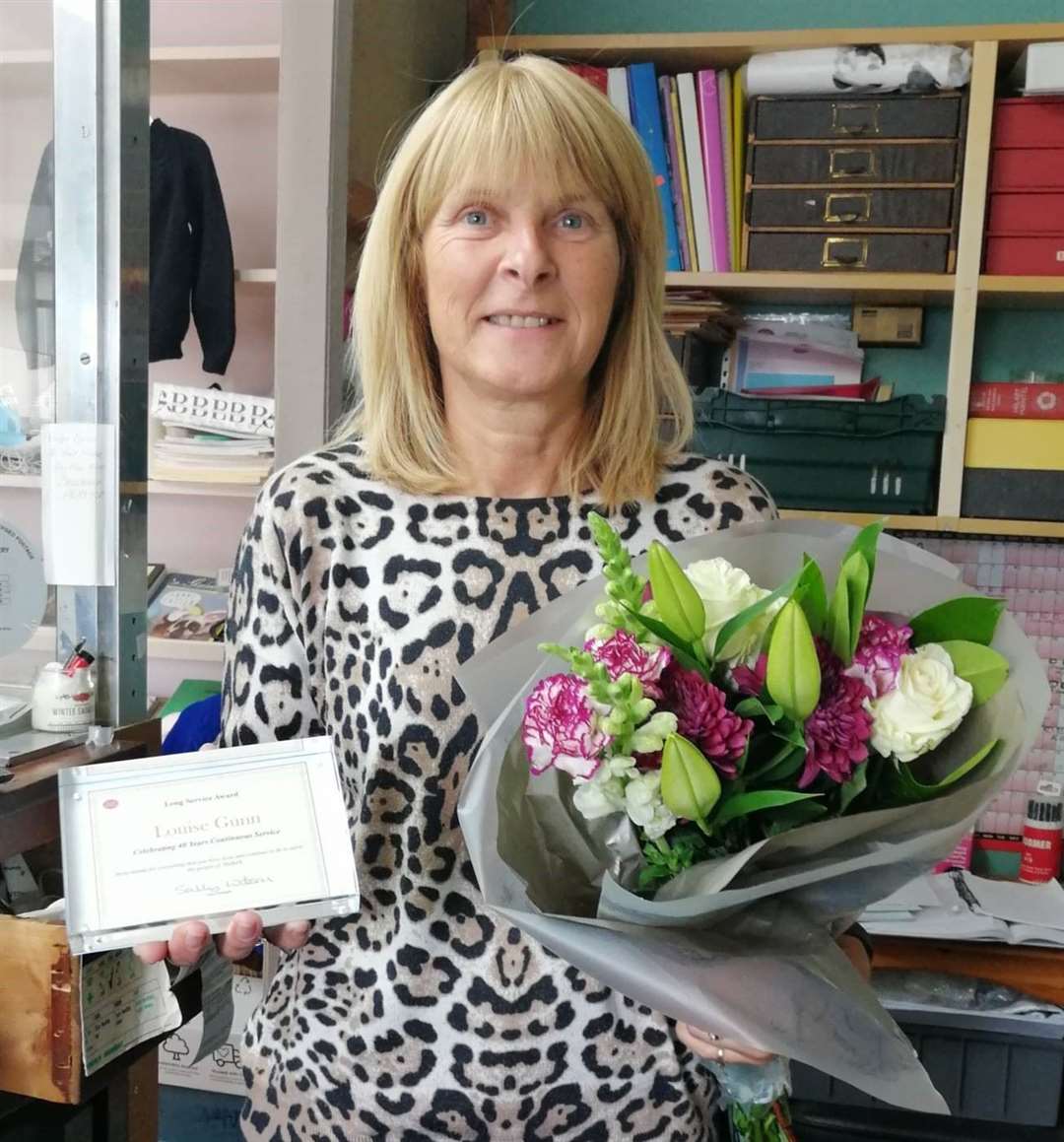 Halkirk postmaster Louise Gunn with her long service award and flowers.