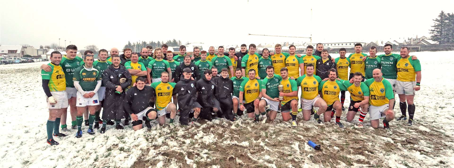 Caithness and the Exiles/Students line up in a mini-blizzard after the annual Sinclair Cadzow memorial match. Captains Marc Anderson and Stuart Kirk are holding the cup. Picture: James Gunn