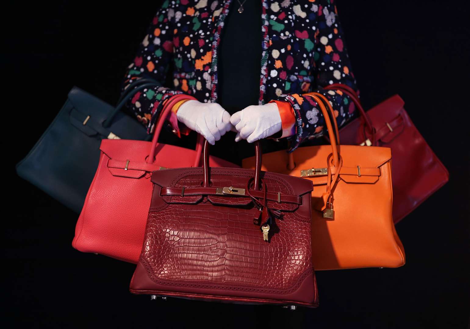 Meg Randell, Head of Designer Handbags and Fashion at Bonhams, holding a range of Birkin bags (Yui Mok/PA)