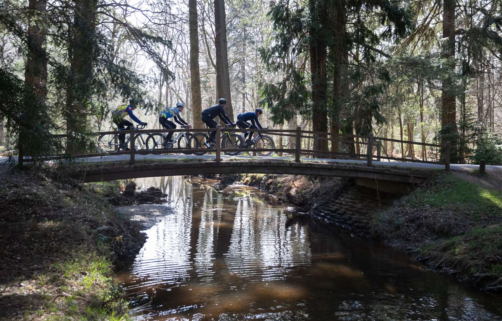 Cyclists cross a bridge over Flechs Water near to Brockenhurst in the New Forest (Andrew Matthews/PA)