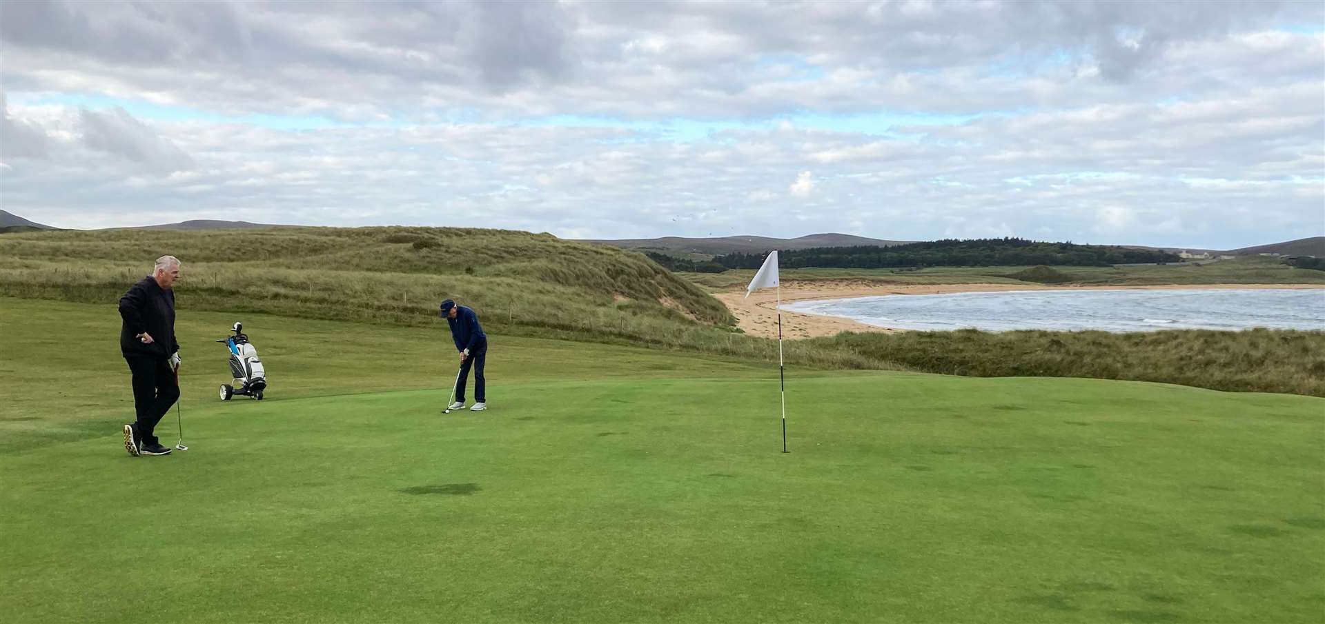Fred Groves putting at the ninth hole in the North Point Distillery Open as Alex Anderson looks on.
