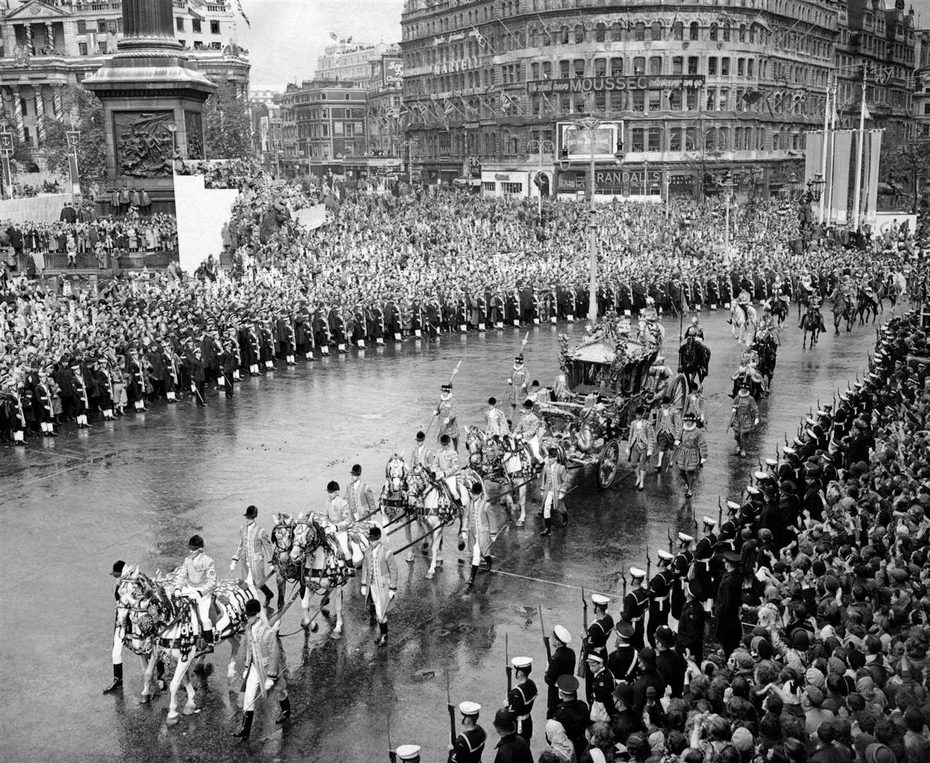 The Gold State Coach, bearing the Queen and the Duke of Edinburgh, passing through the cheering crowds which, despite the rain, packed Trafalgar Square to greet the sovereign on her way from Westminster Abbey to Buckingham Palace after her coronation (PA)