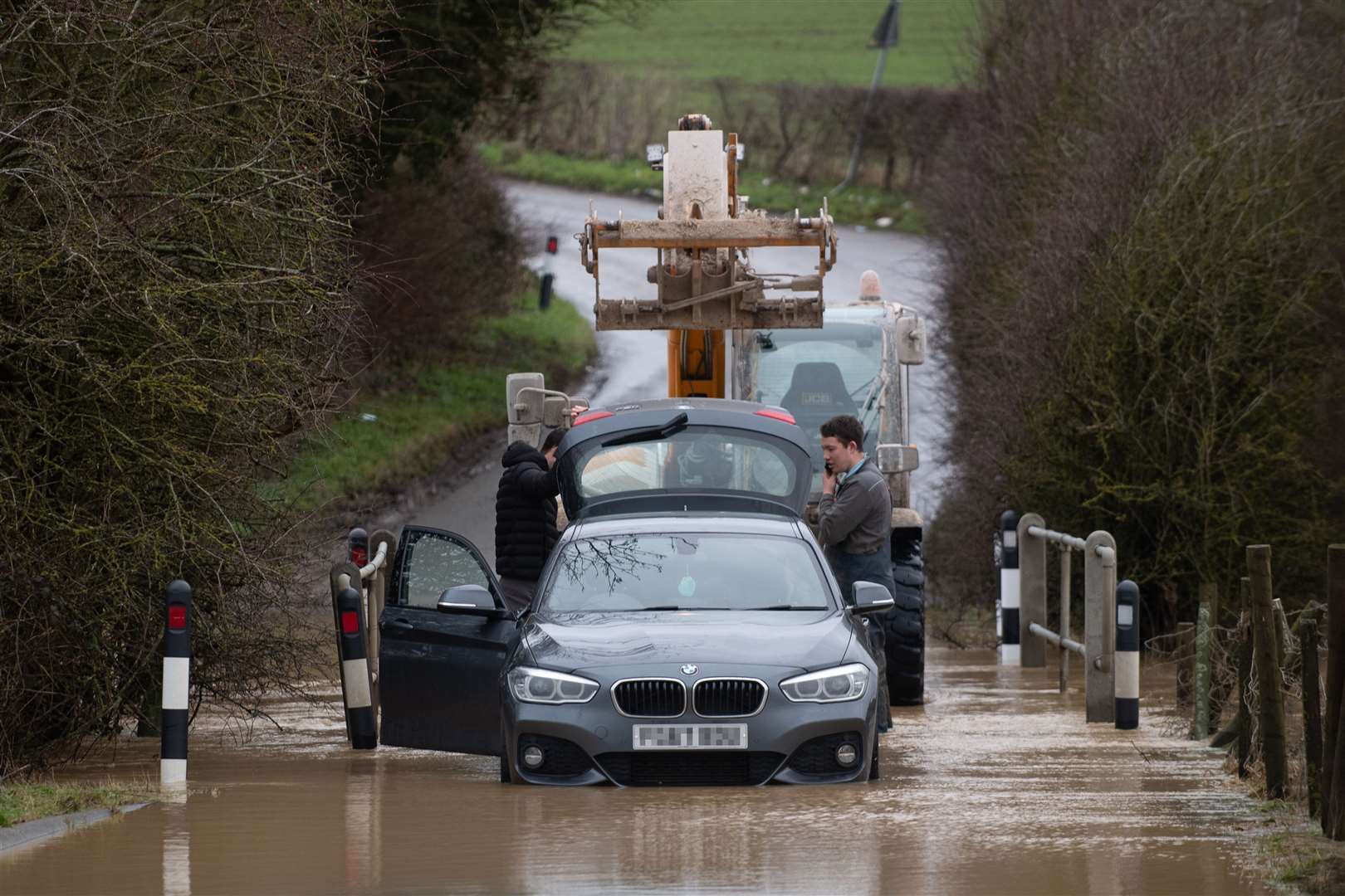 A local farmer helps rescue a stranded motorist from a flood on Hamilton Road in Leicester (Joe Giddens/PA)