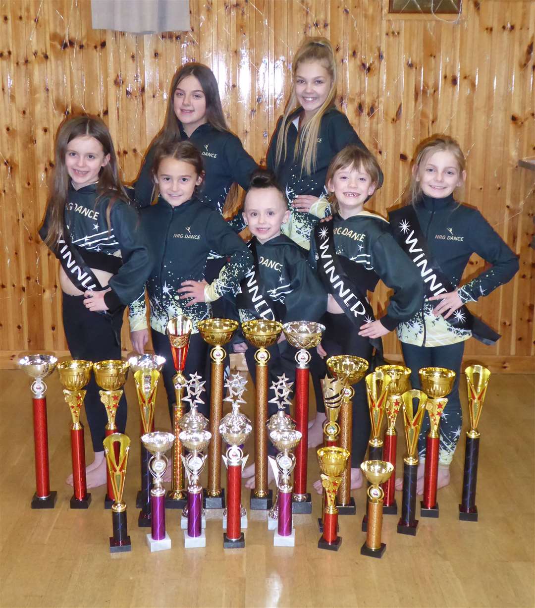 Members of NRG Dance's competitive team with their trophies.