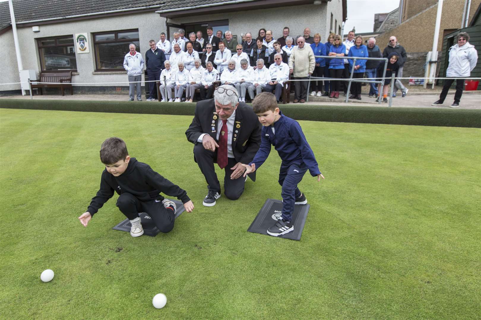 St Fergus president Malky Mackay watches as his two grandsons – seven-year-old Harry Heaton (left) and three-year-old Calum – throw the first jacks of the season. Looking on are some of the other members of the club along with invited guests. Picture: Robert MacDonald / Northern Studios