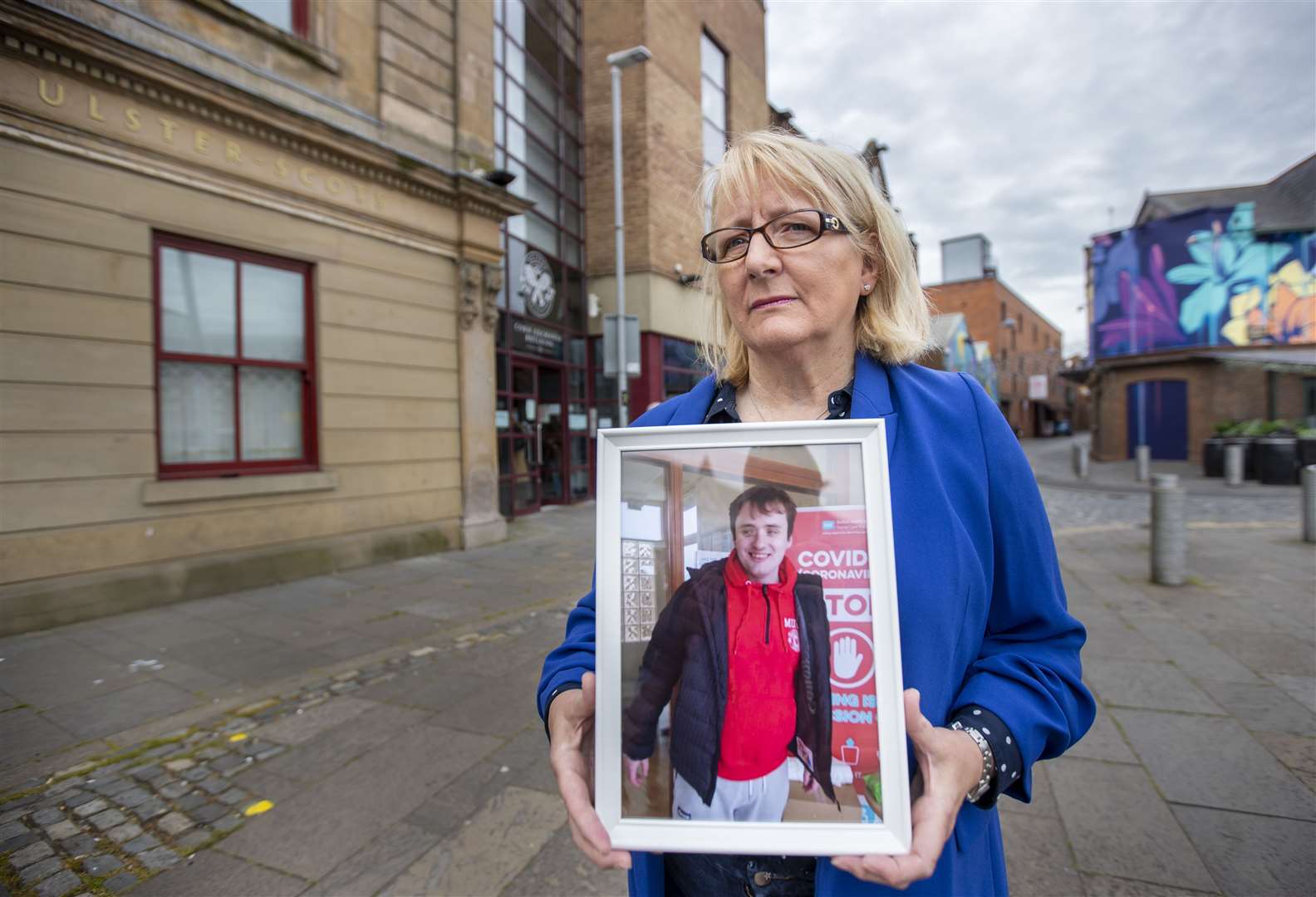 Dawn Jones outside the Corn Exchange, Cathedral Quarter in Belfast, holding an image of her son Timothy, who was a patient at Muckamore Abbey Hospital (Liam McBurney/PA)