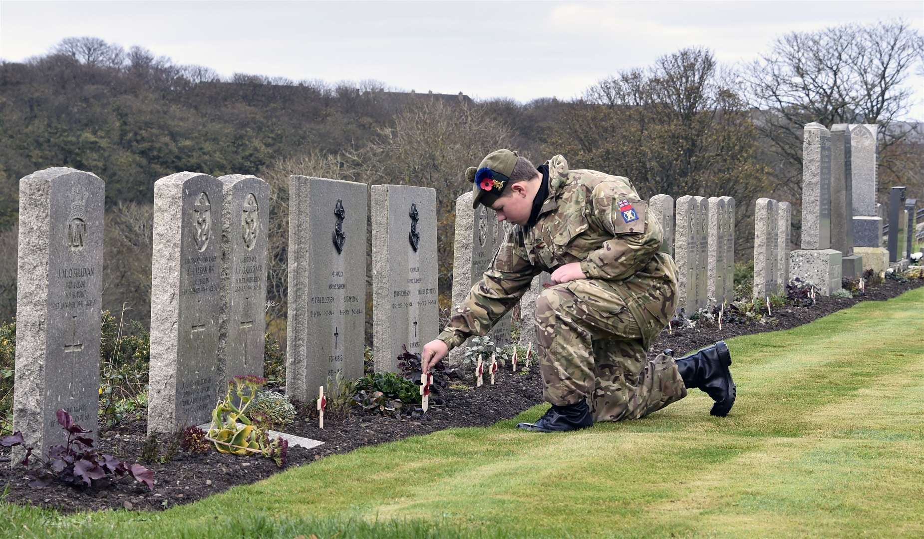 An army cadet placing a poppy cross on one of the war graves at Thurso cemetery. Picture: Mel Roger