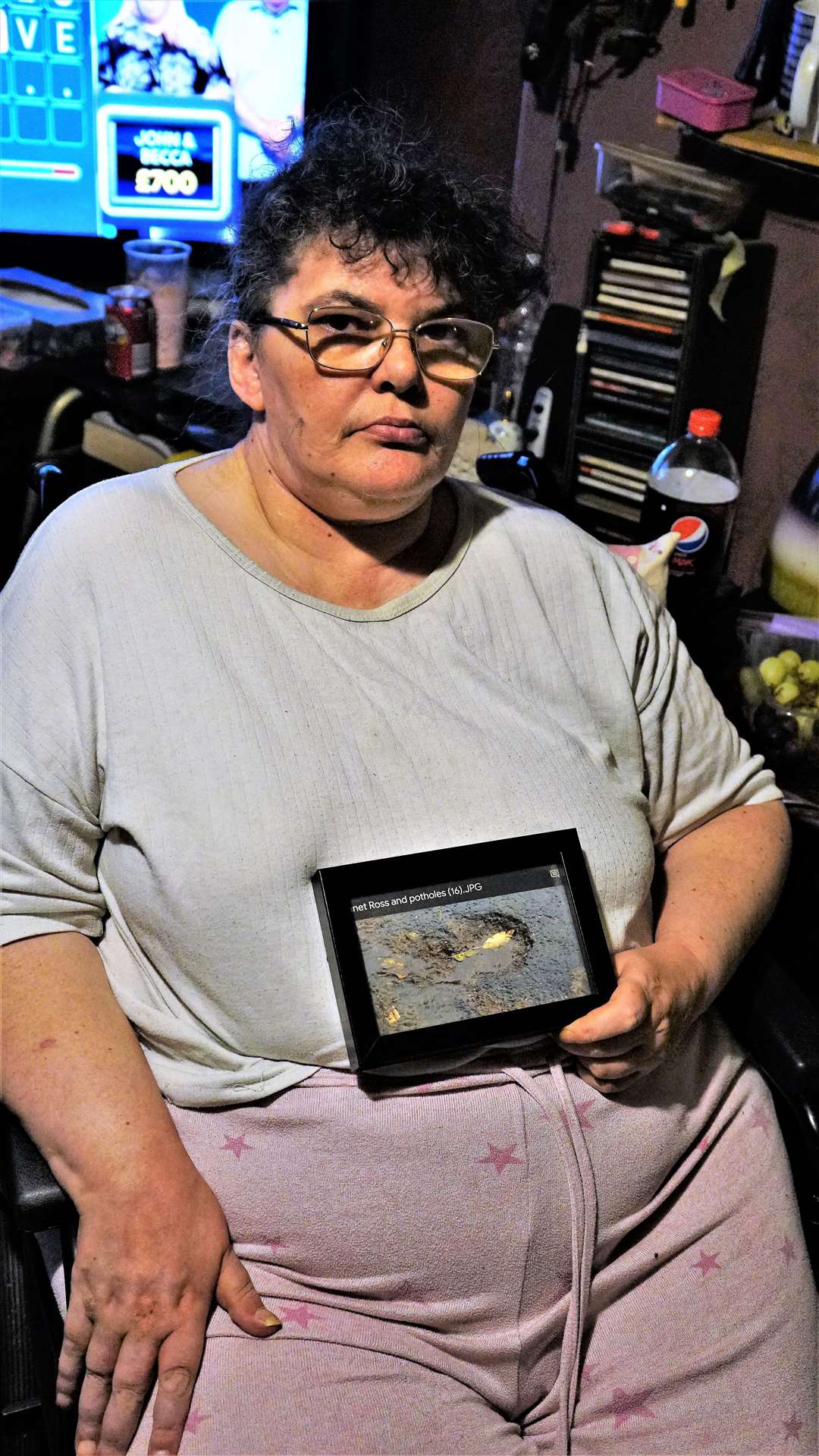 Janet has framed a picture of the pothole that caused her so much pain and misery. Picture: DGS